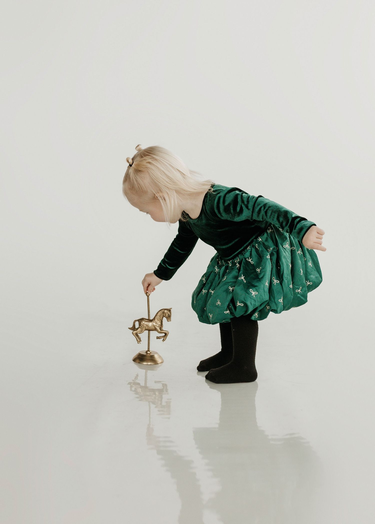 little girl  dressed for christmas playing with a horse