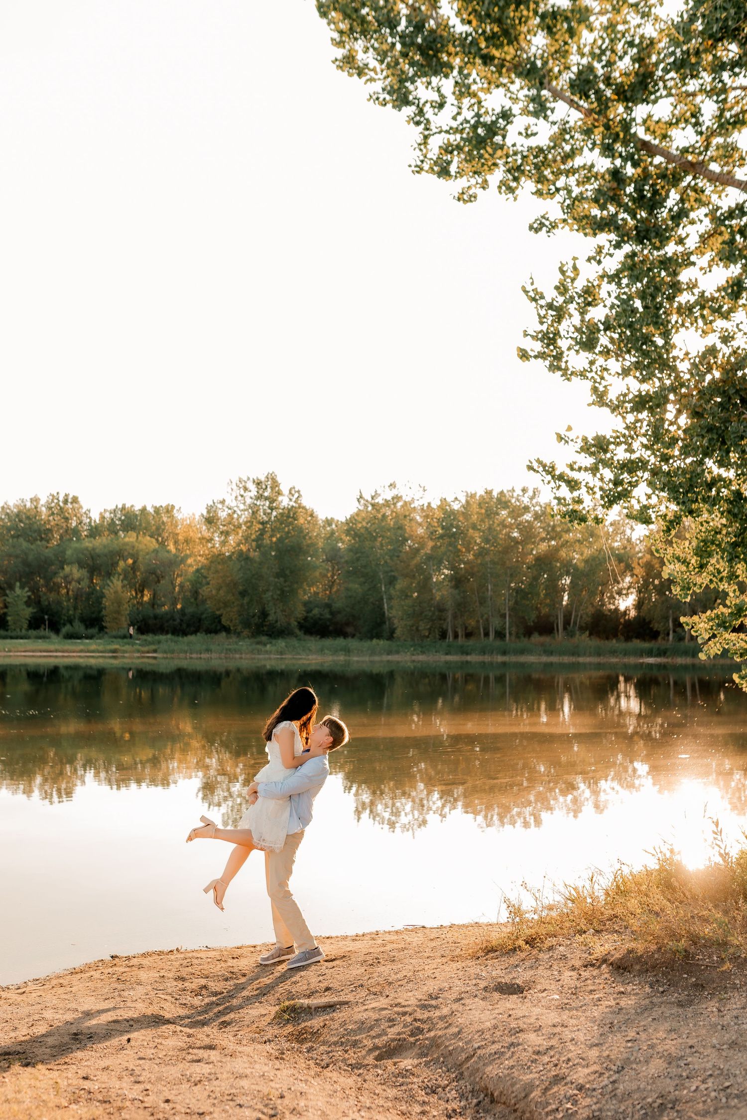 Couple dancing together at sunset by a serene lake with trees in the background  by brookings south dakota