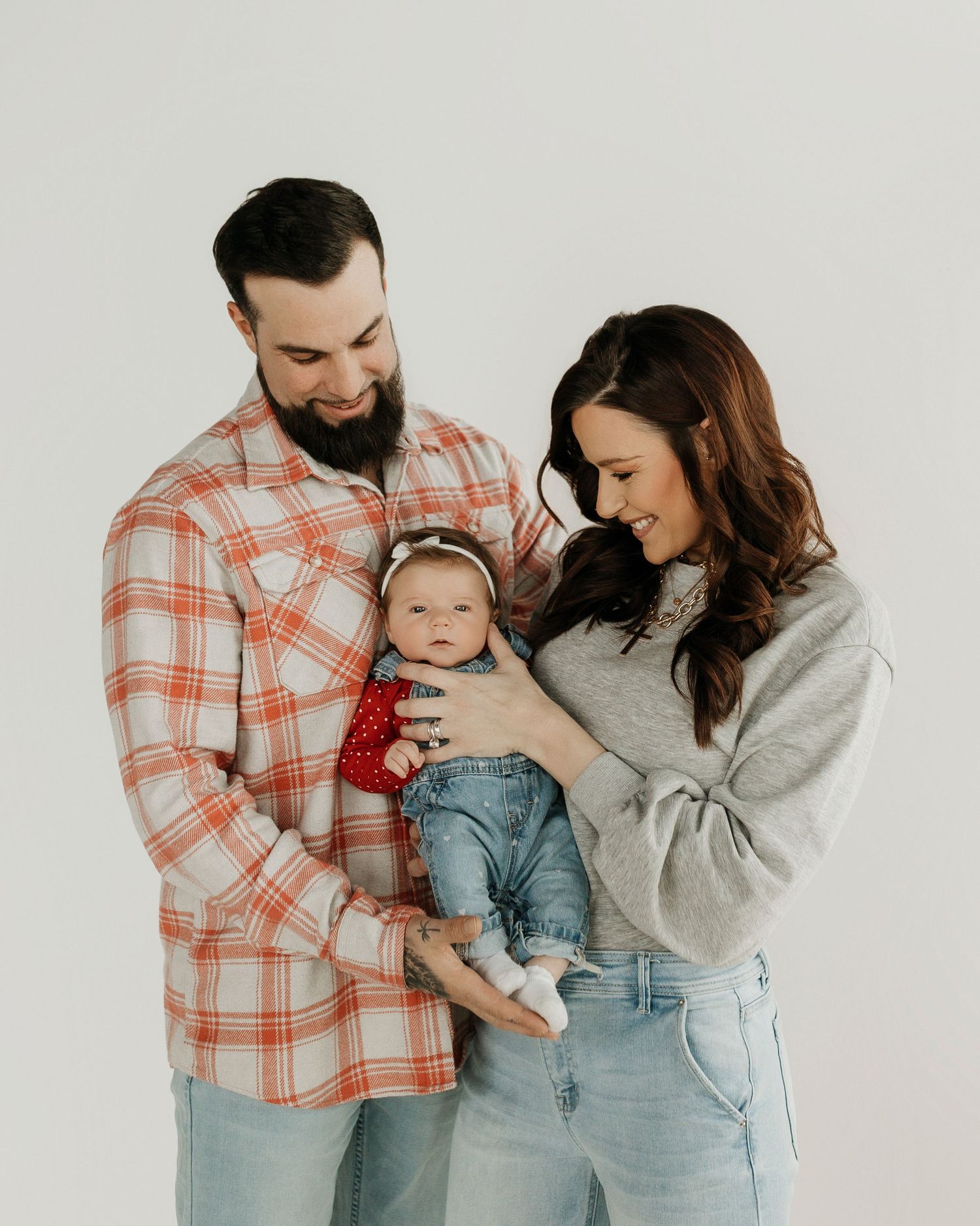 small family in christmas attire smiling and holding their new baby