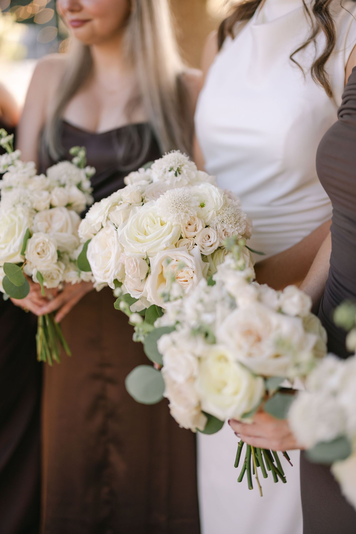 A bride and her bridesmaids hold their dainty and classic bouquets together on a wedding day