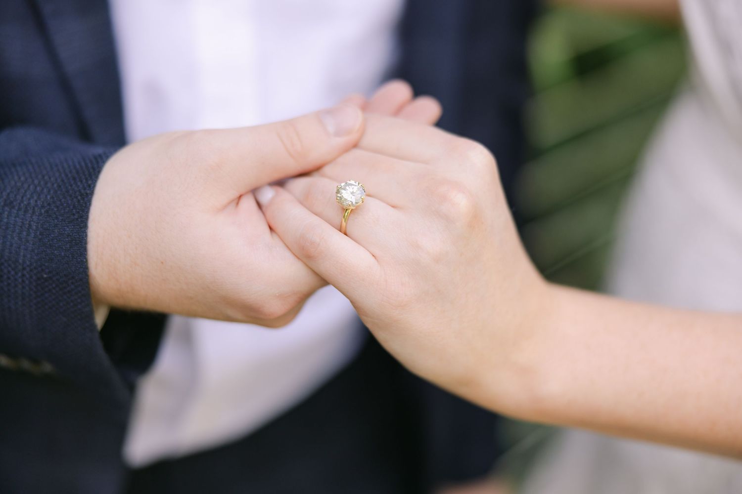A man delicately holds the hand of a woman he just proposed to. Her stunning diamond ring is the focal point. LOUISIANA WEDDING PHOTOGRAPHER