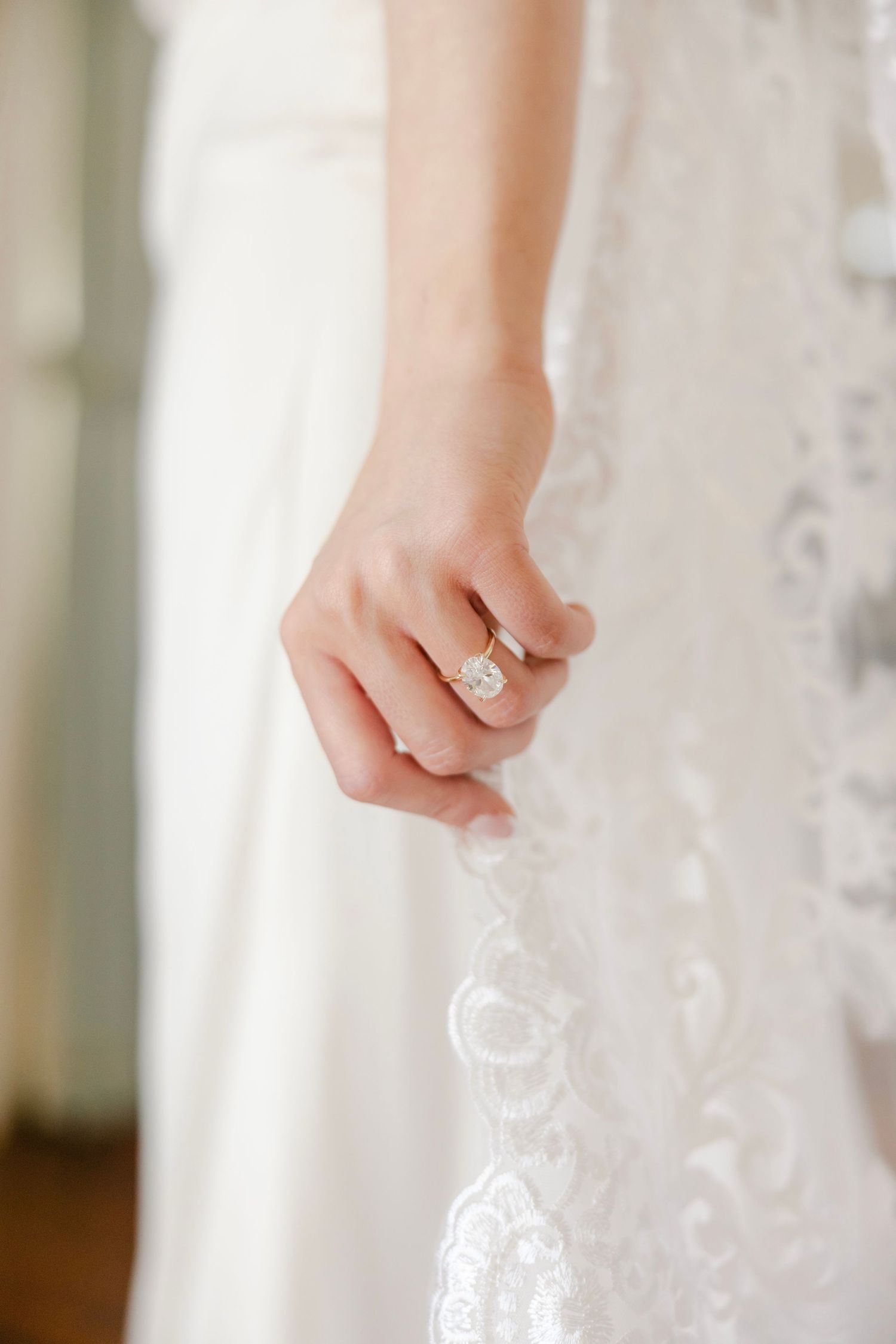 A bride delicately holds the trim of her veil with her ring hand. Her stunning diamond ring LOUISIANA WEDDING PHOTOGRAPHER ARLINGTON MANSION