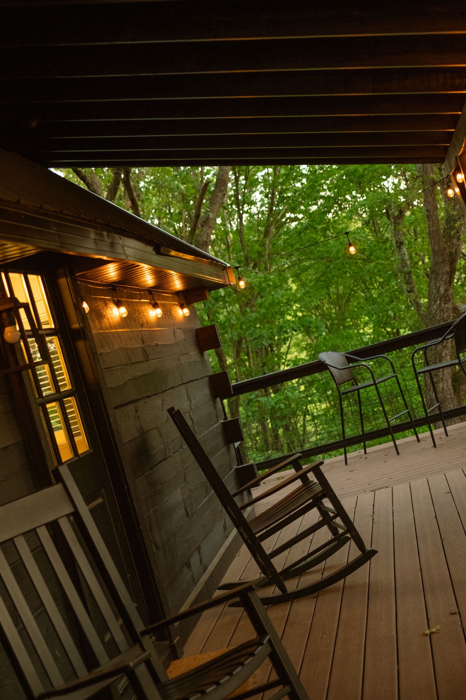 Rustic porch with rocking chairs and string lights creating a cozy evening atmosphere.