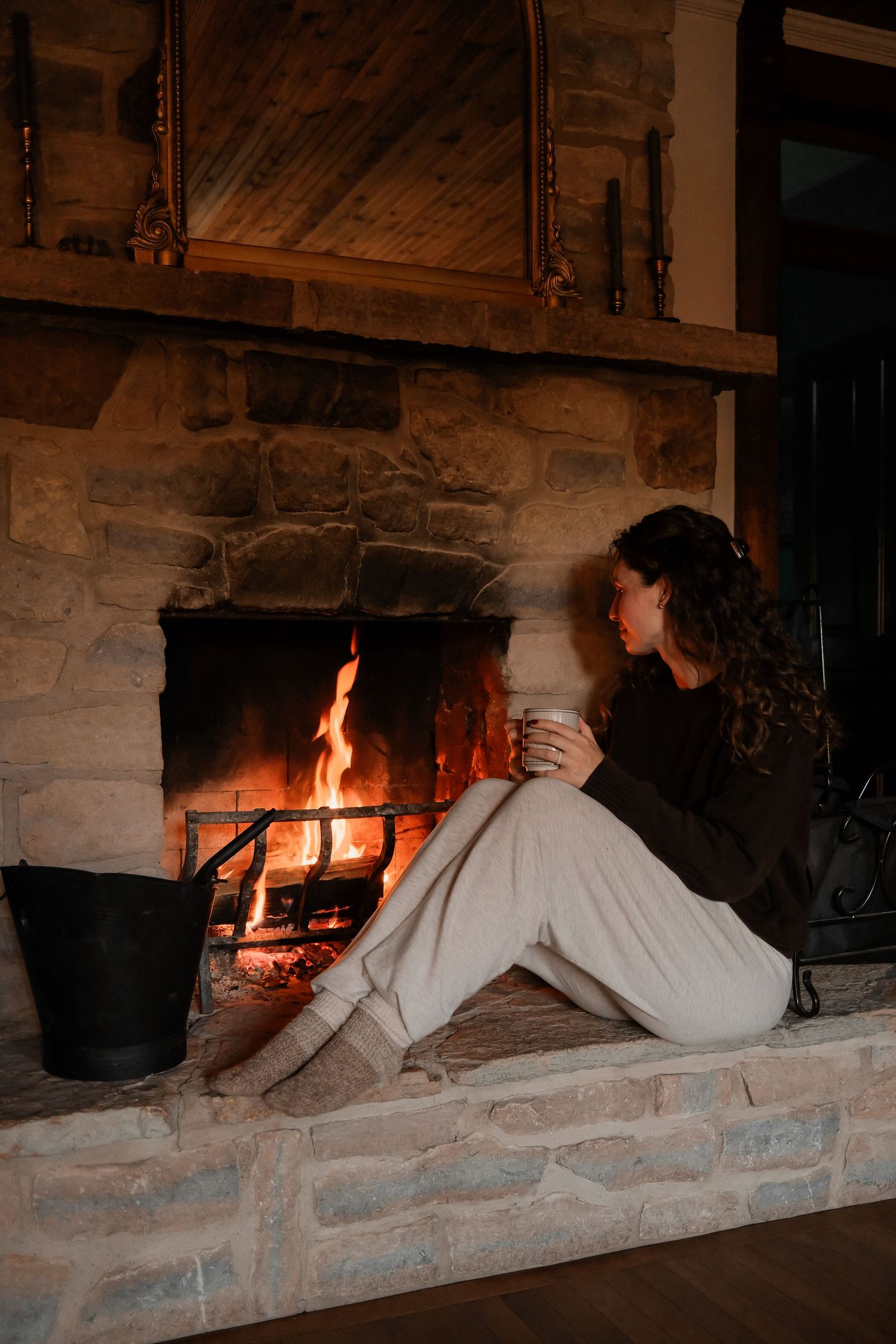 Cozy fireside scene with stone fireplace and warm glowing flames.