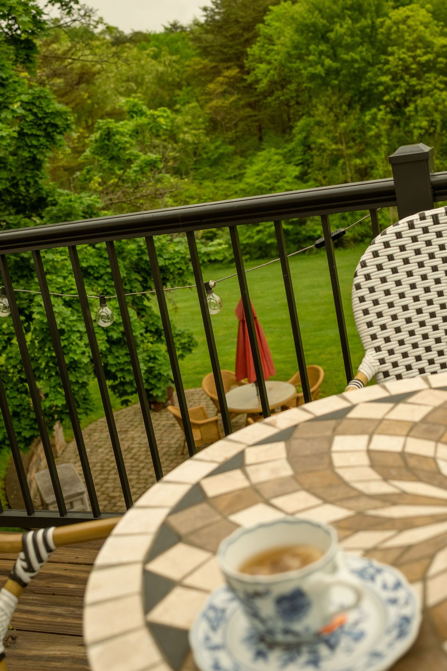 Outdoor deck railing with teacup and saucer casting shadows in morning light.