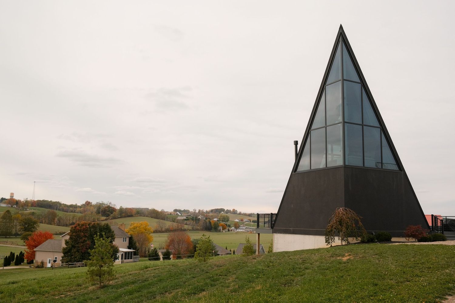 Striking black triangular building with geometric design set against rural landscape.
