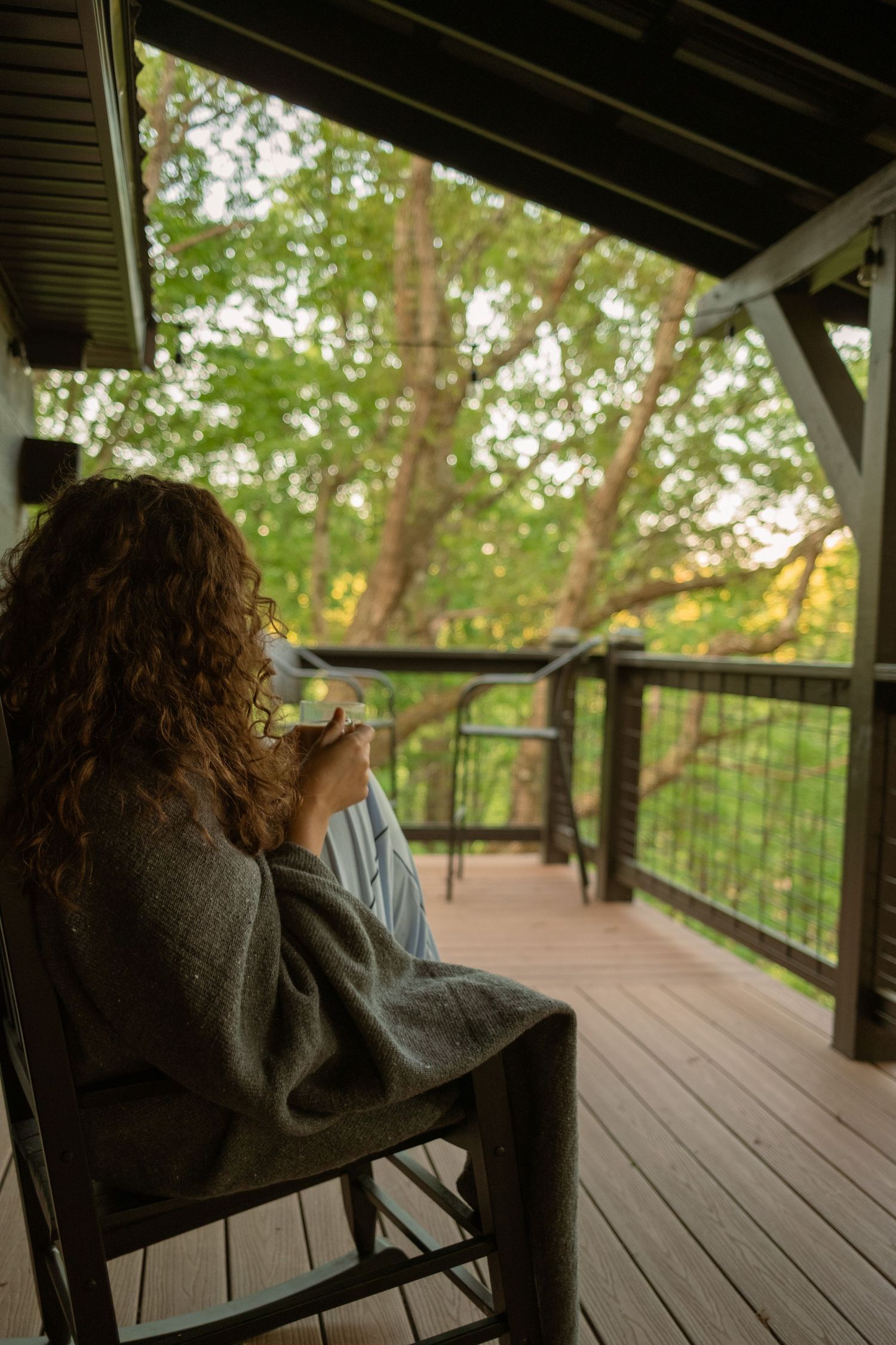Wooden deck railing overlooking a forested area during golden hour.