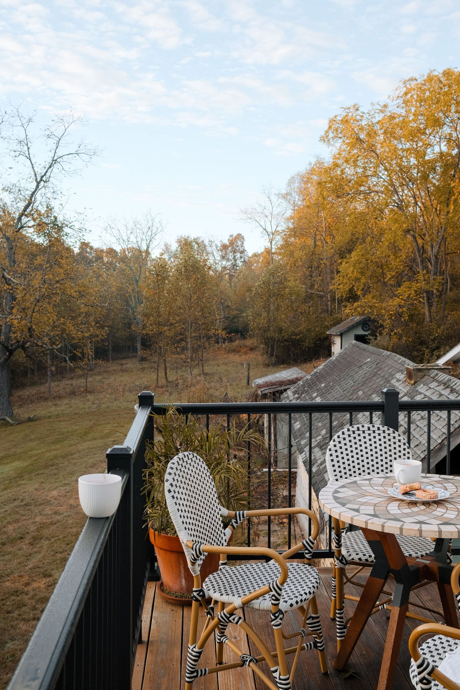 Outdoor deck with bistro chairs overlooking a golden autumn landscape at sunset.