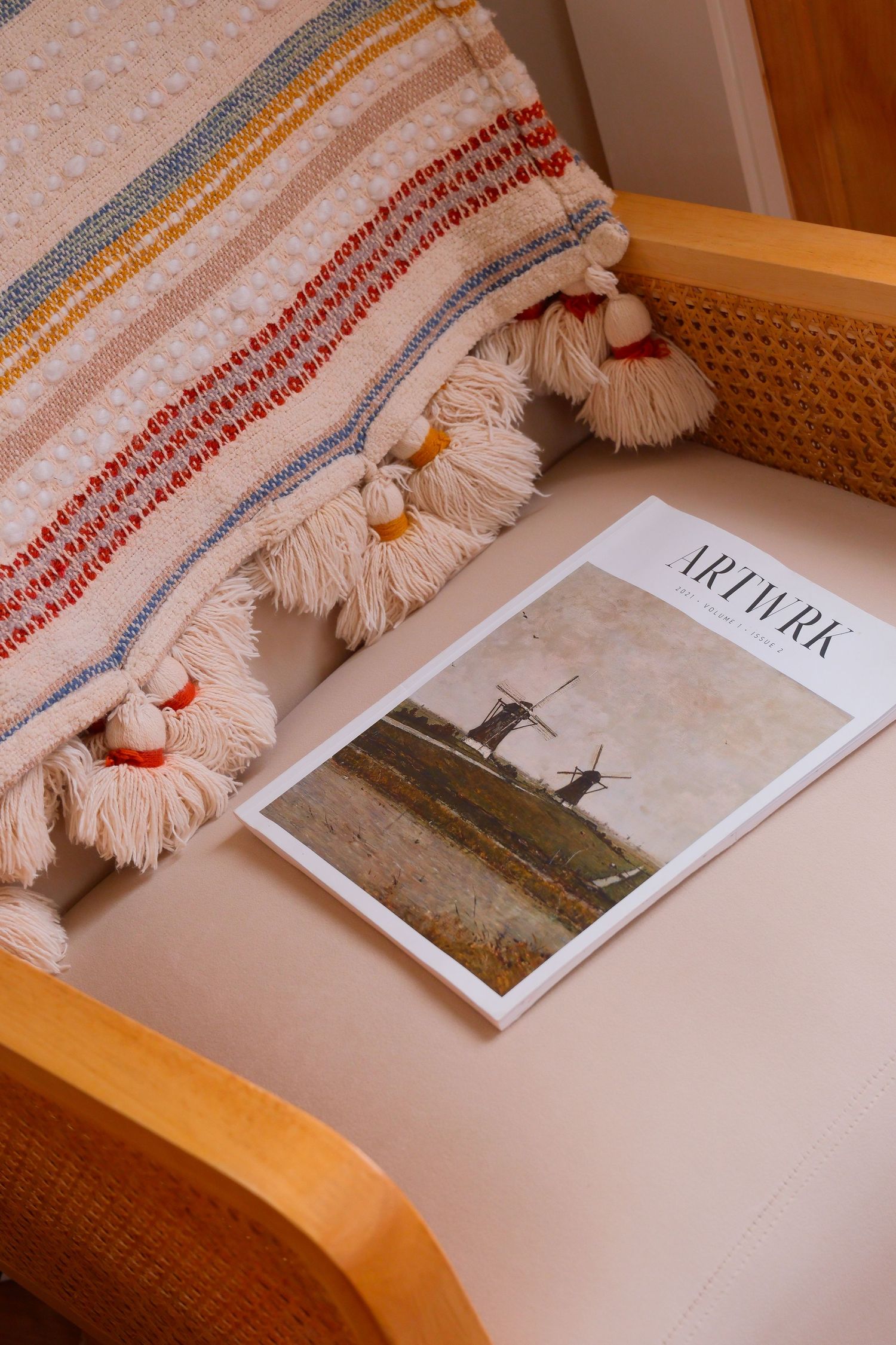 Artirk magazine with windmill cover photo on a beige chair with a striped tassel blanket.