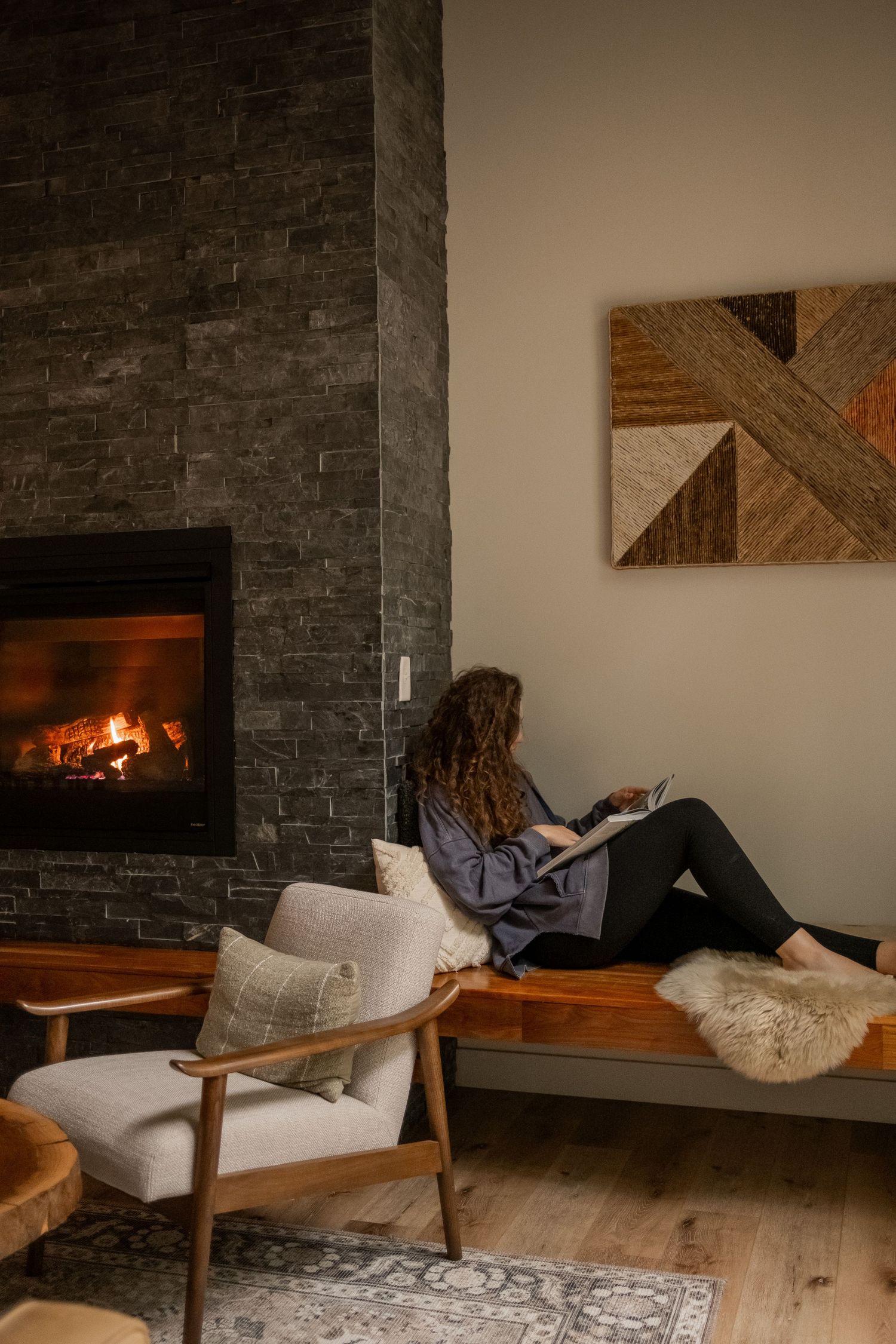 Cozy reading nook with stone fireplace and modern geometric wall art.