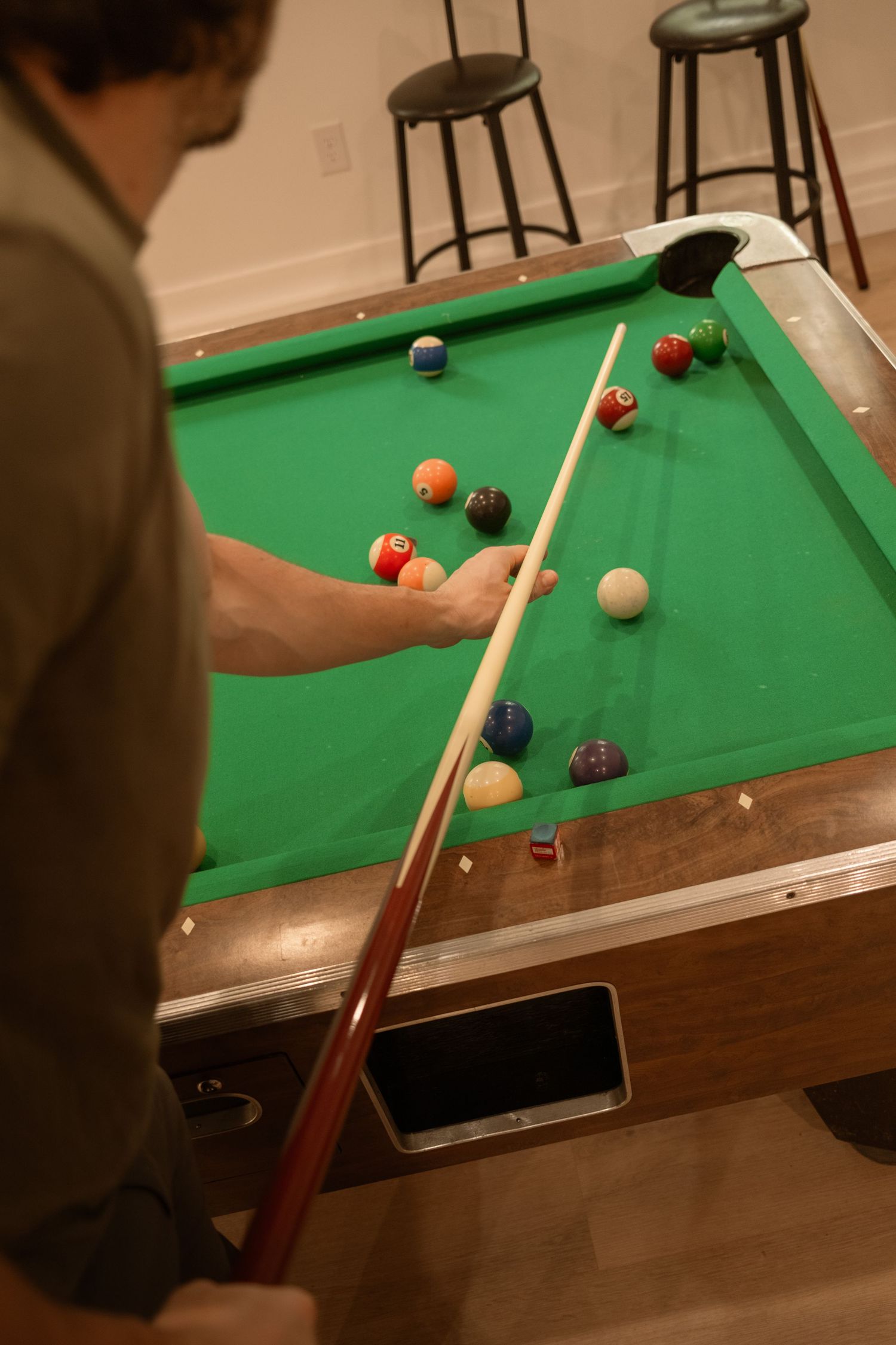 Close-up view of pool game in progress on green felt table with scattered billiard balls.