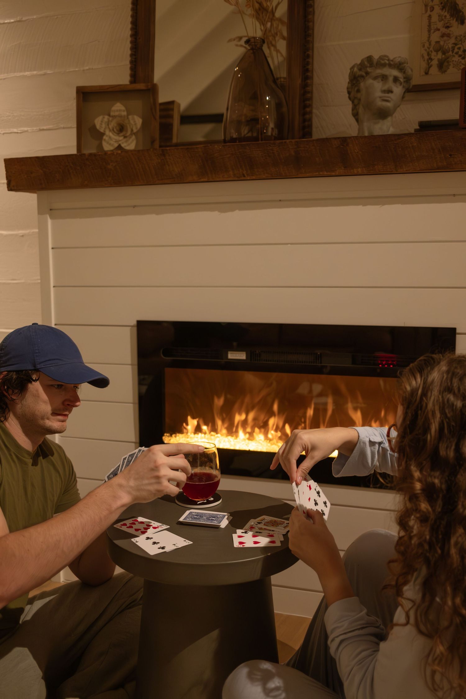 Card game being played by fireplace in cozy cabin interior.