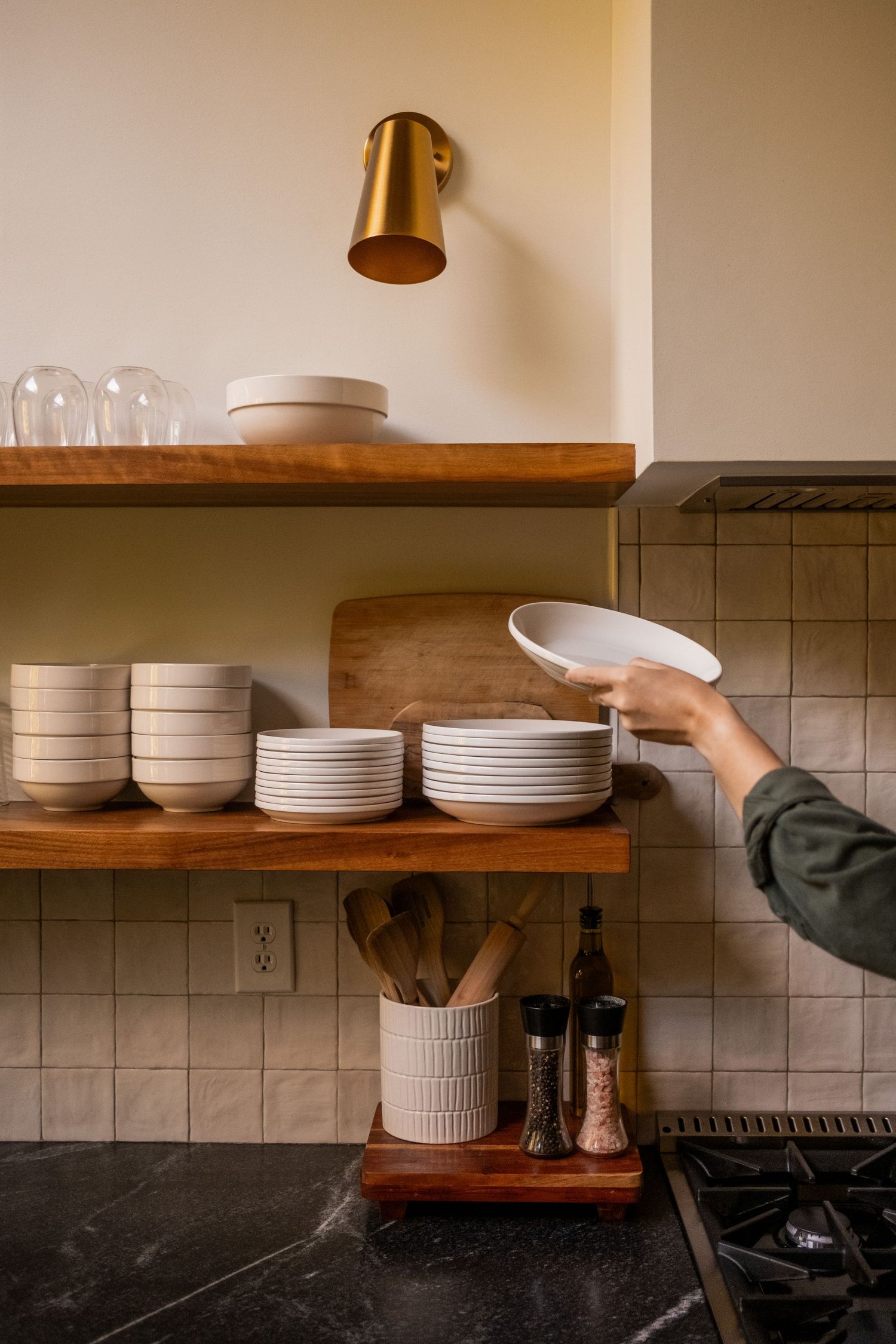 Wooden open shelving displaying white dinnerware in a modern kitchen setting.