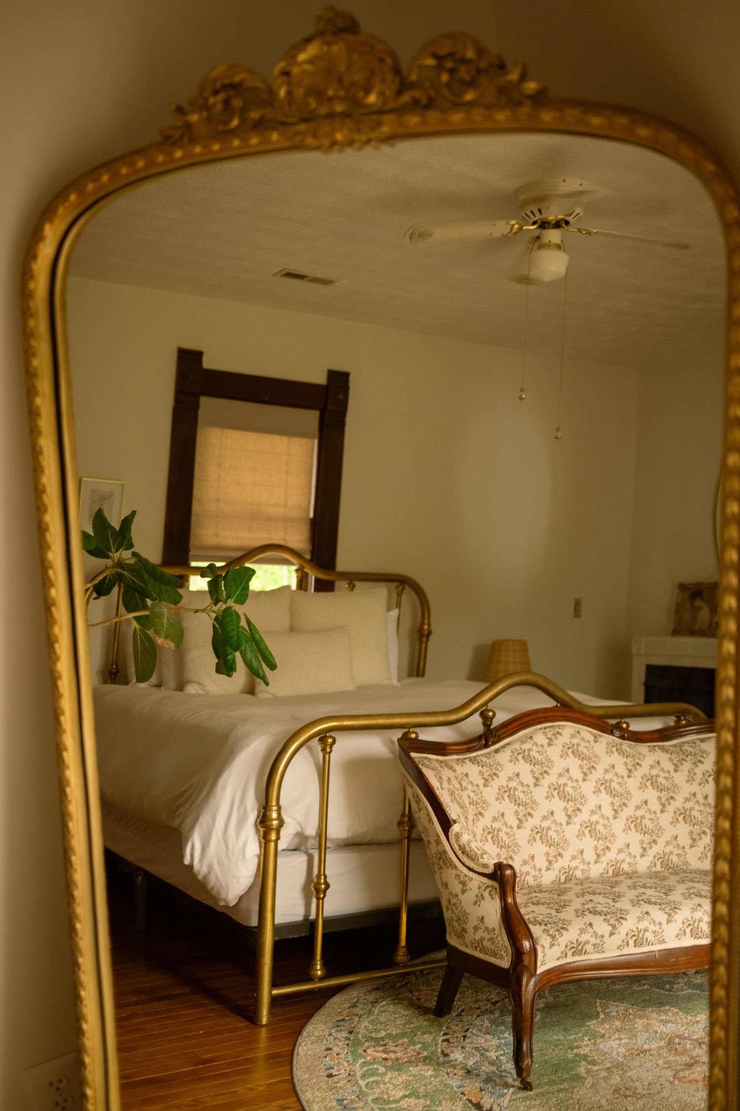 Elegant bedroom featuring an ornate gold mirror and antique-style furniture with damask upholstery.