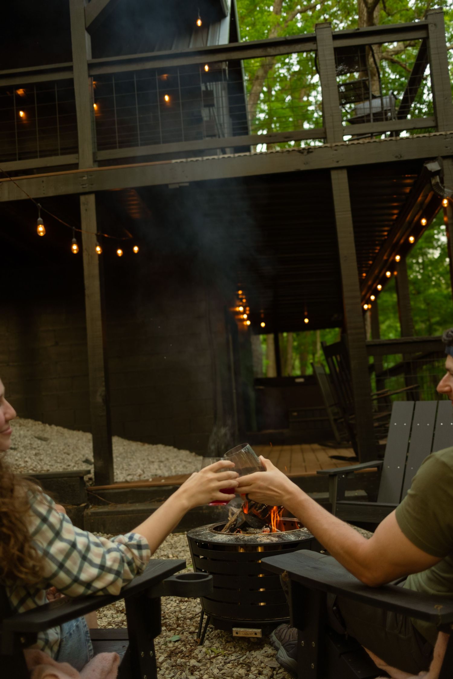 Outdoor seating area with string lights and a fire pit creating an evening ambiance.