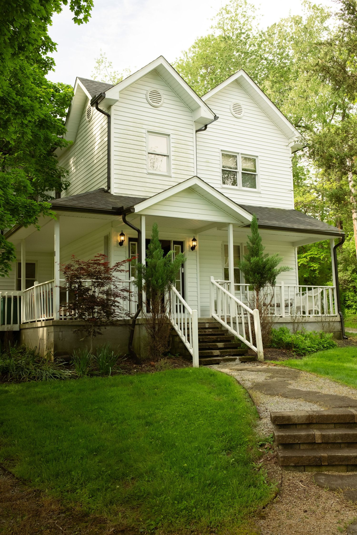 White farmhouse-style cottages with porches nestled on a green hillside.