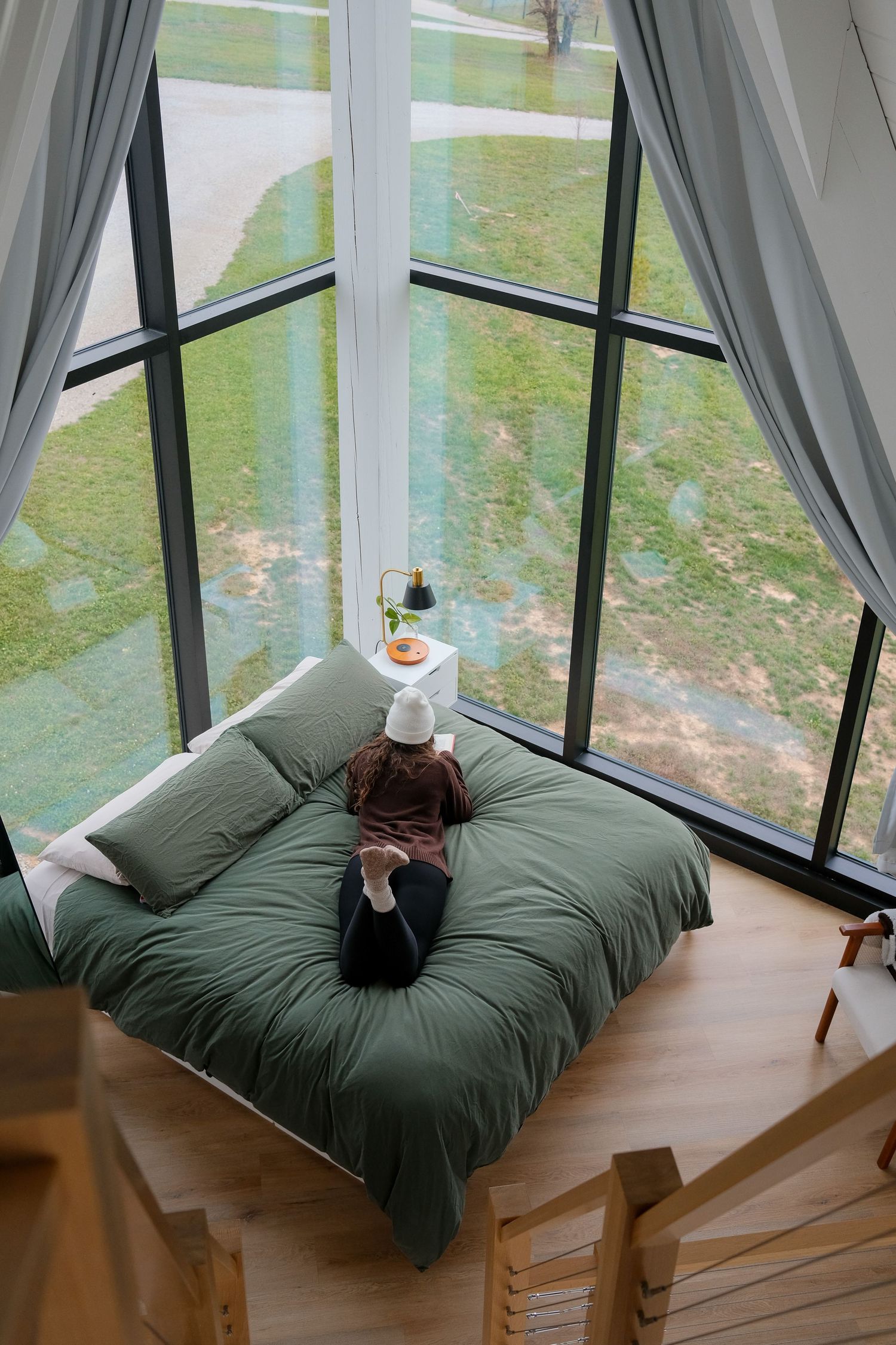 Comfortable lounge area with floor cushions and panoramic windows overlooking green landscape.