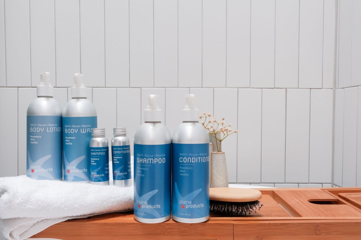 A collection of blue and white personal care products arranged on a wooden shelf with a towel and hairbrush.