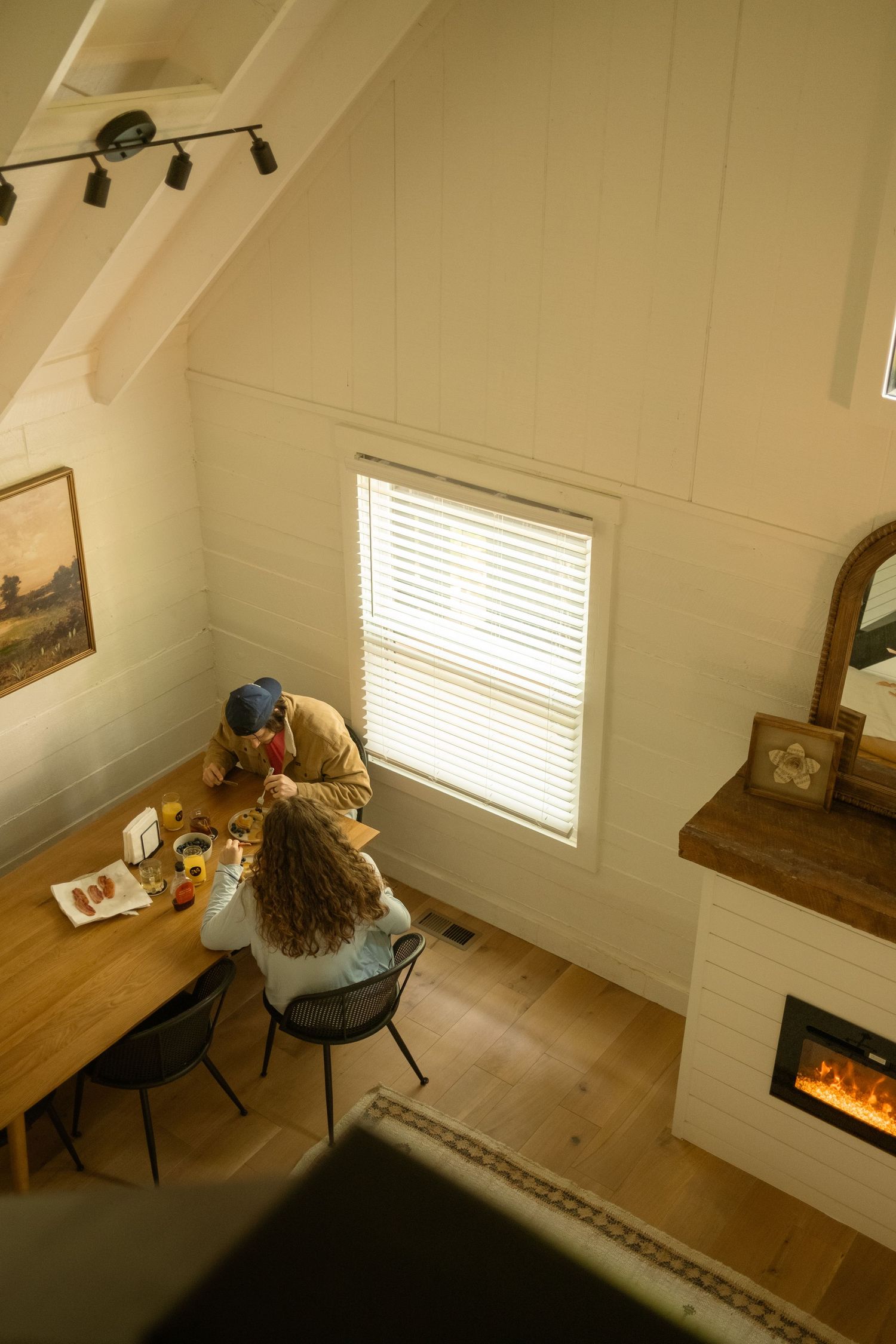 Modern white interior room with wooden floors and electric fireplace.