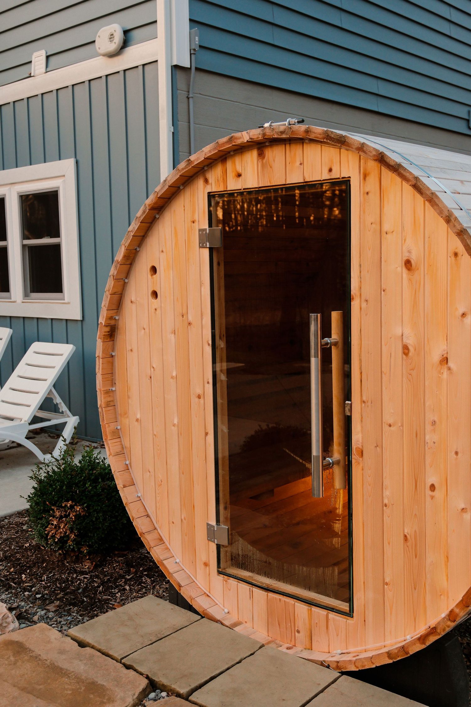 Five sequential images showing the installation process of a circular wooden sauna door on a blue house exterior.