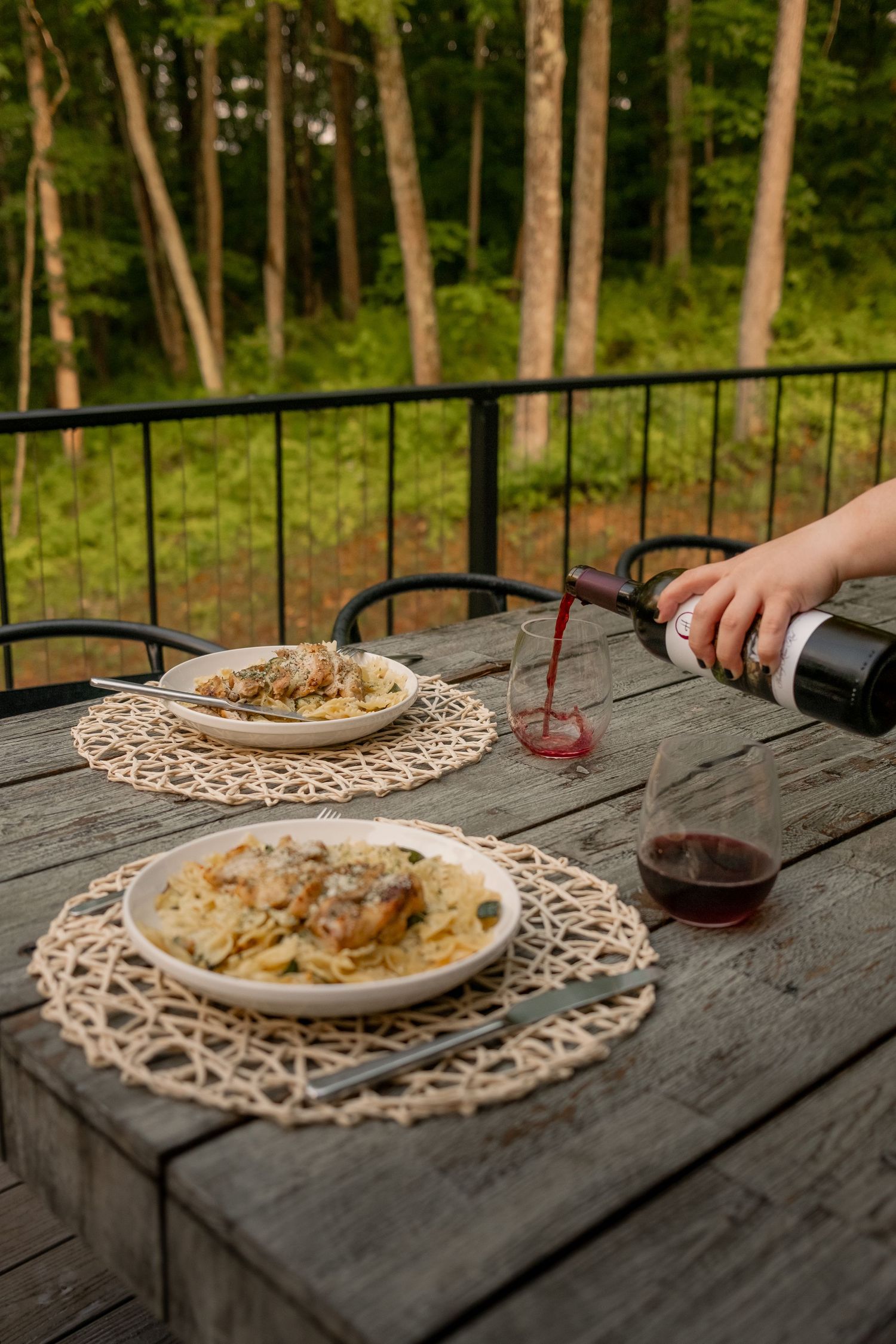 Pasta dishes served on lace doilies on a rustic wooden outdoor table.