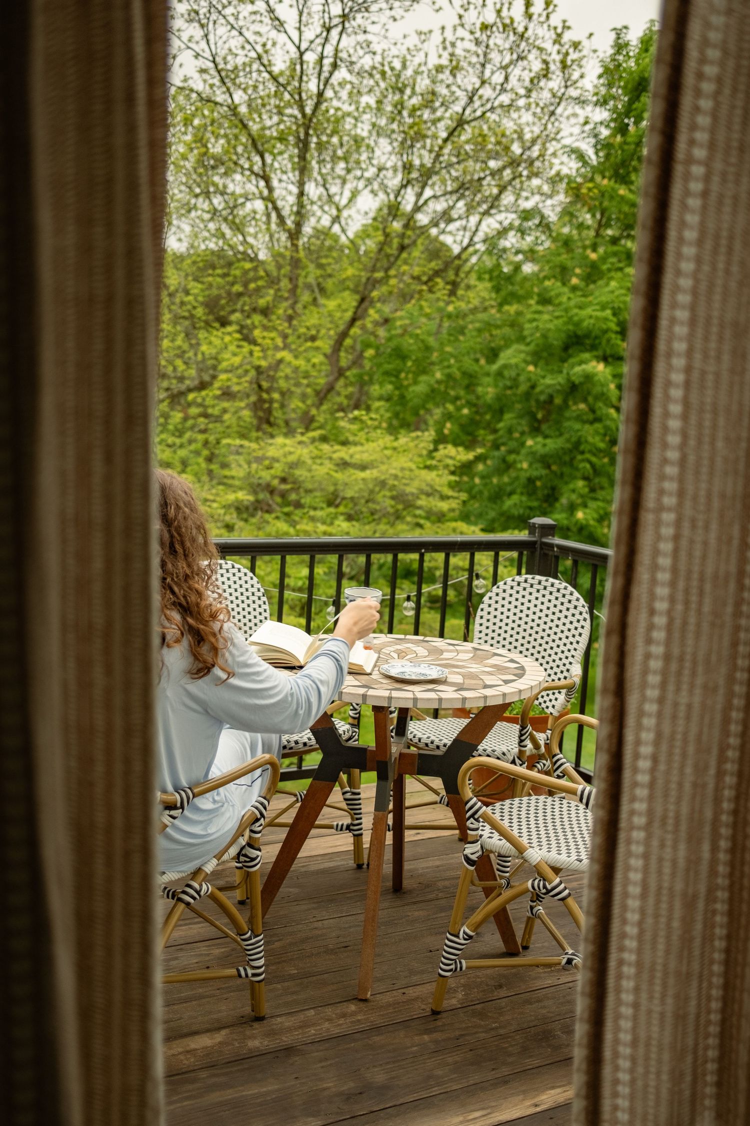 Outdoor dining area with white wicker chairs and round table on a covered porch.