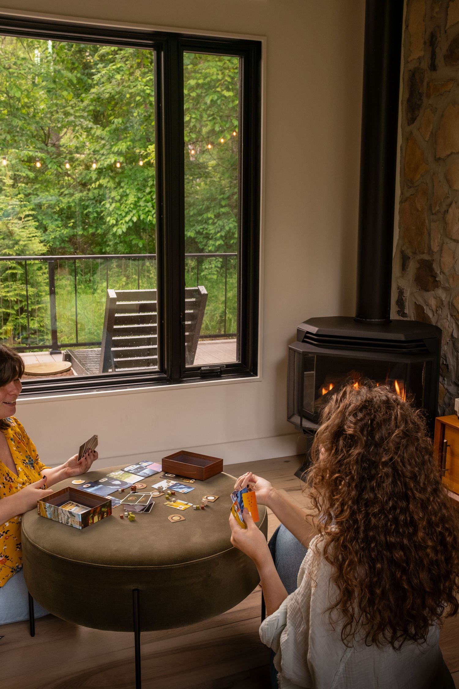 Room with large windows overlooking forest scenery and comfortable seating.