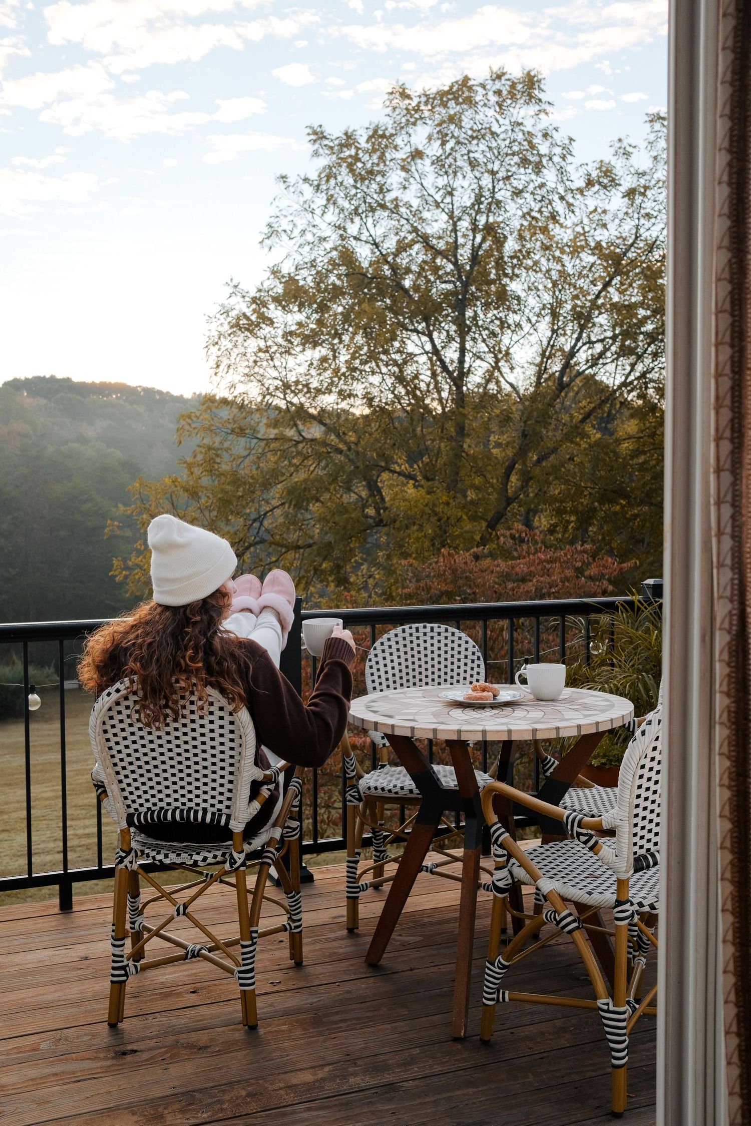 Bistro-style patio furniture arranged on a wooden deck overlooking a scenic autumn landscape.