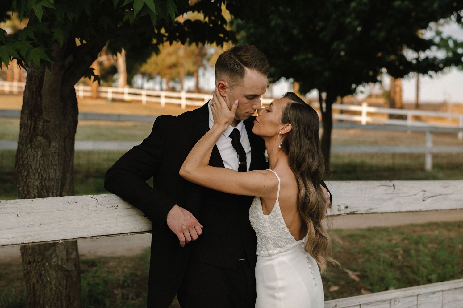 bride and groom leaning against a fence at the rolling waters venue