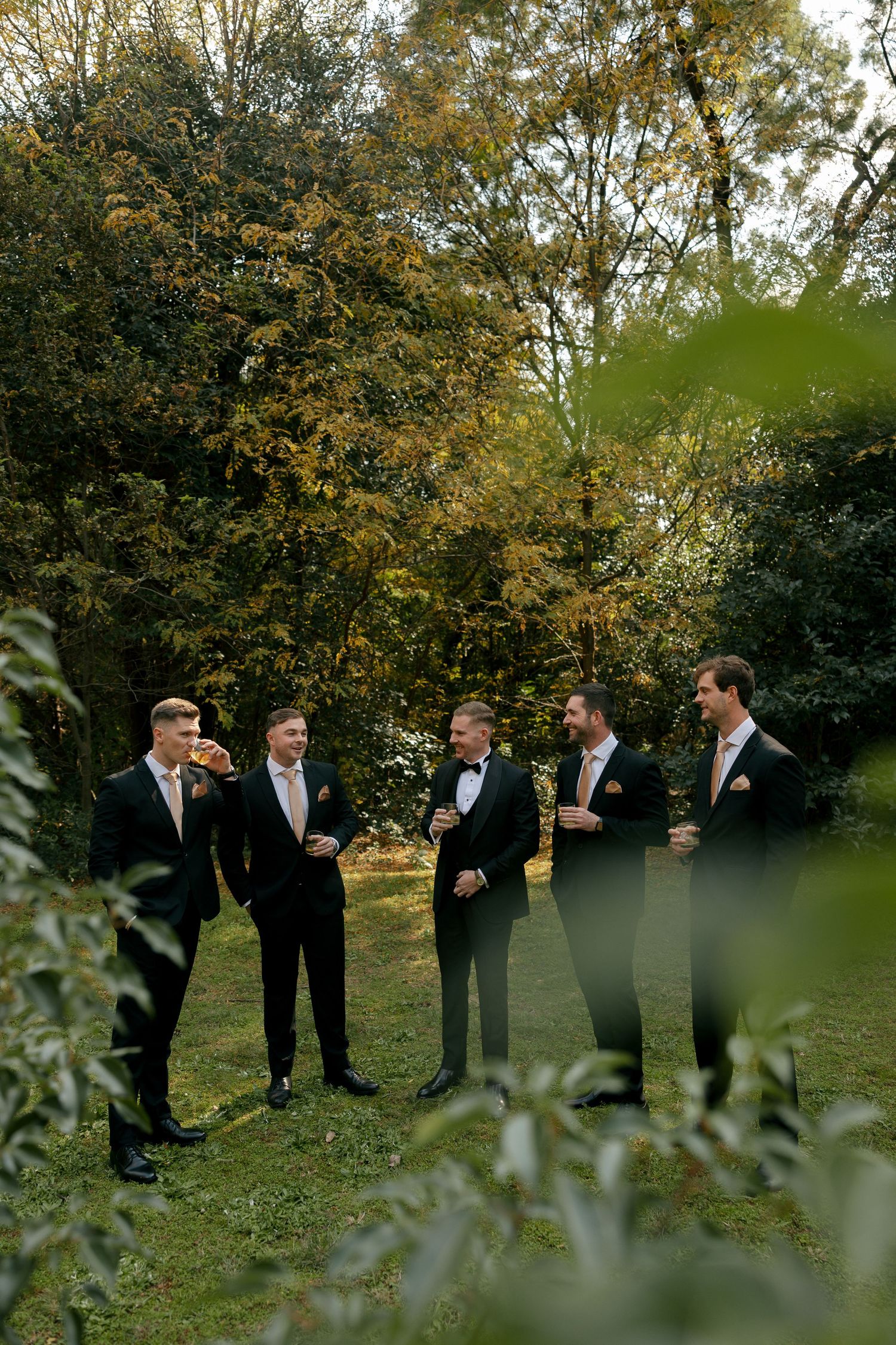 groom and his groomsmen standing having a drink before getting ready