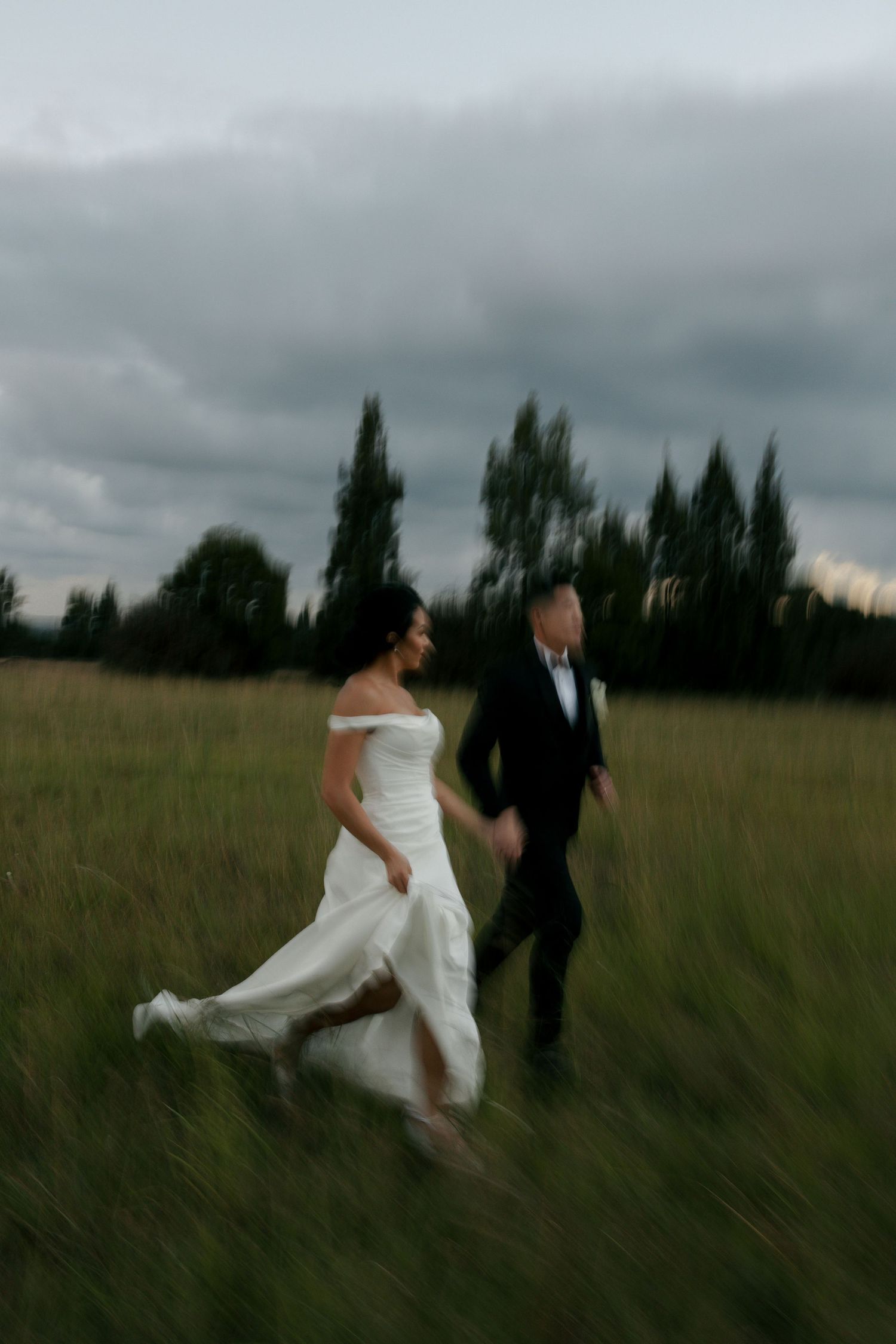 bride and groom running in a field of grass at greenhouse cafe