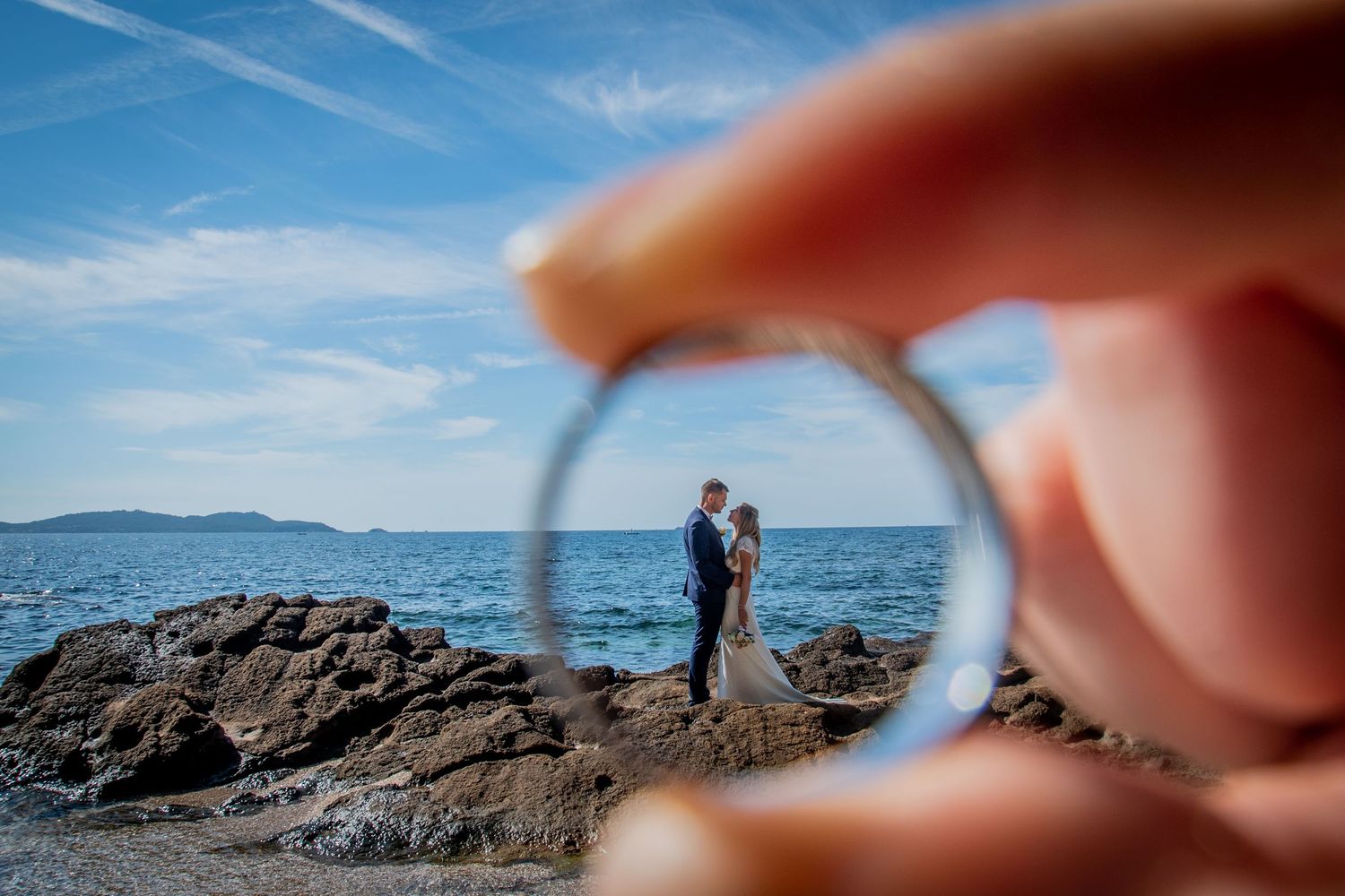 Creative ring photography with ocean and rocky coastline in background.