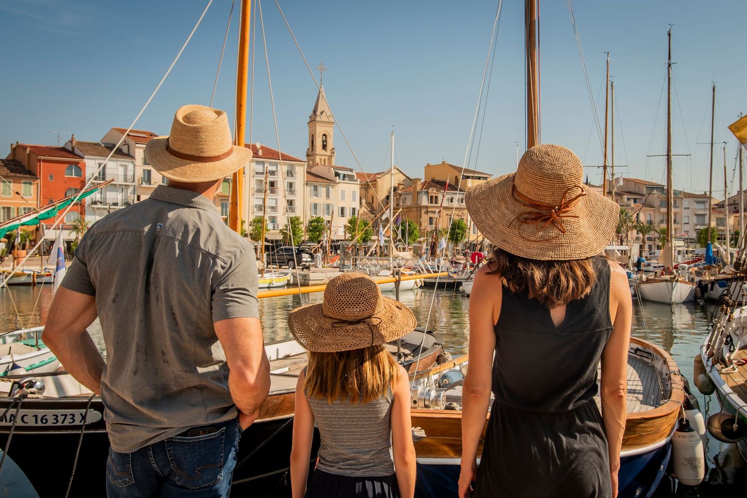 People enjoying scenic waterfront views of boats and buildings from a marina walkway.