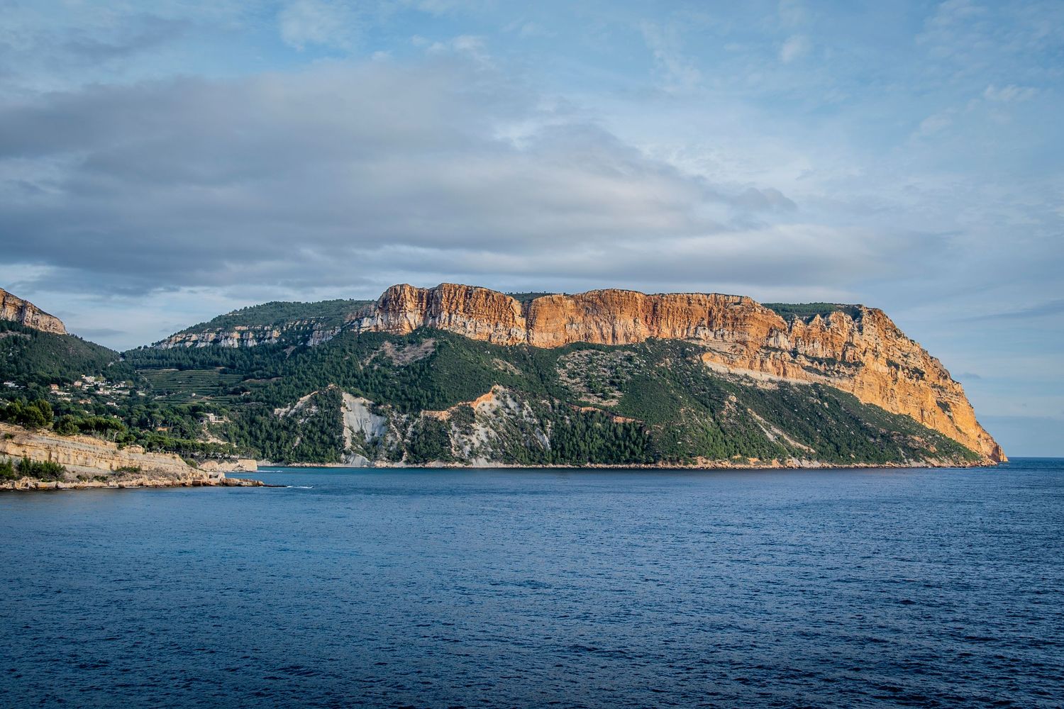 Dramatic coastal cliff landscape with Mediterranean sea view in golden sunlight.
