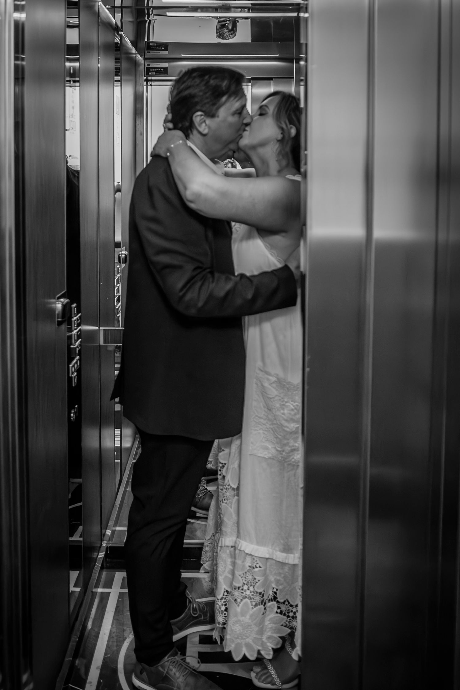 Intimate black and white moment captured in an elevator setting.