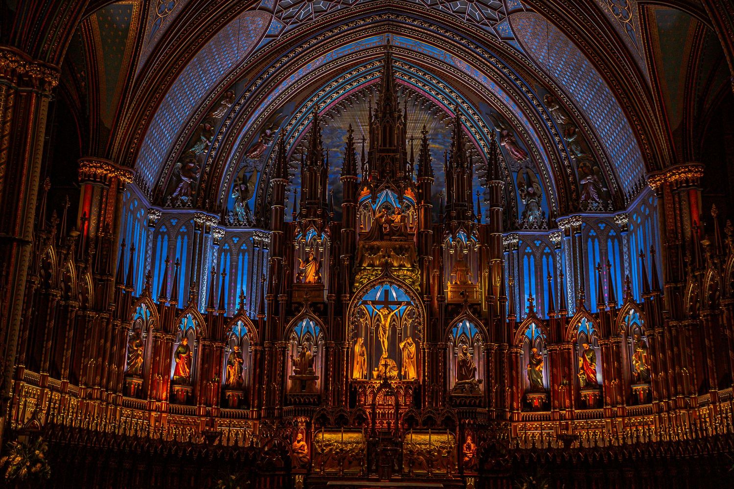 Ornate golden altar and blue-lit gothic architecture inside the historic Notre-Dame Basilica in Montreal at night.