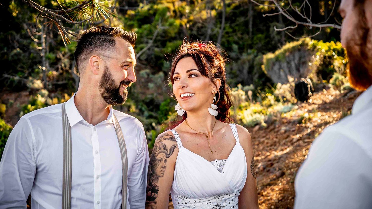 A newlywed couple shares intimate moments in an outdoor setting with warm natural lighting and forest backdrop.