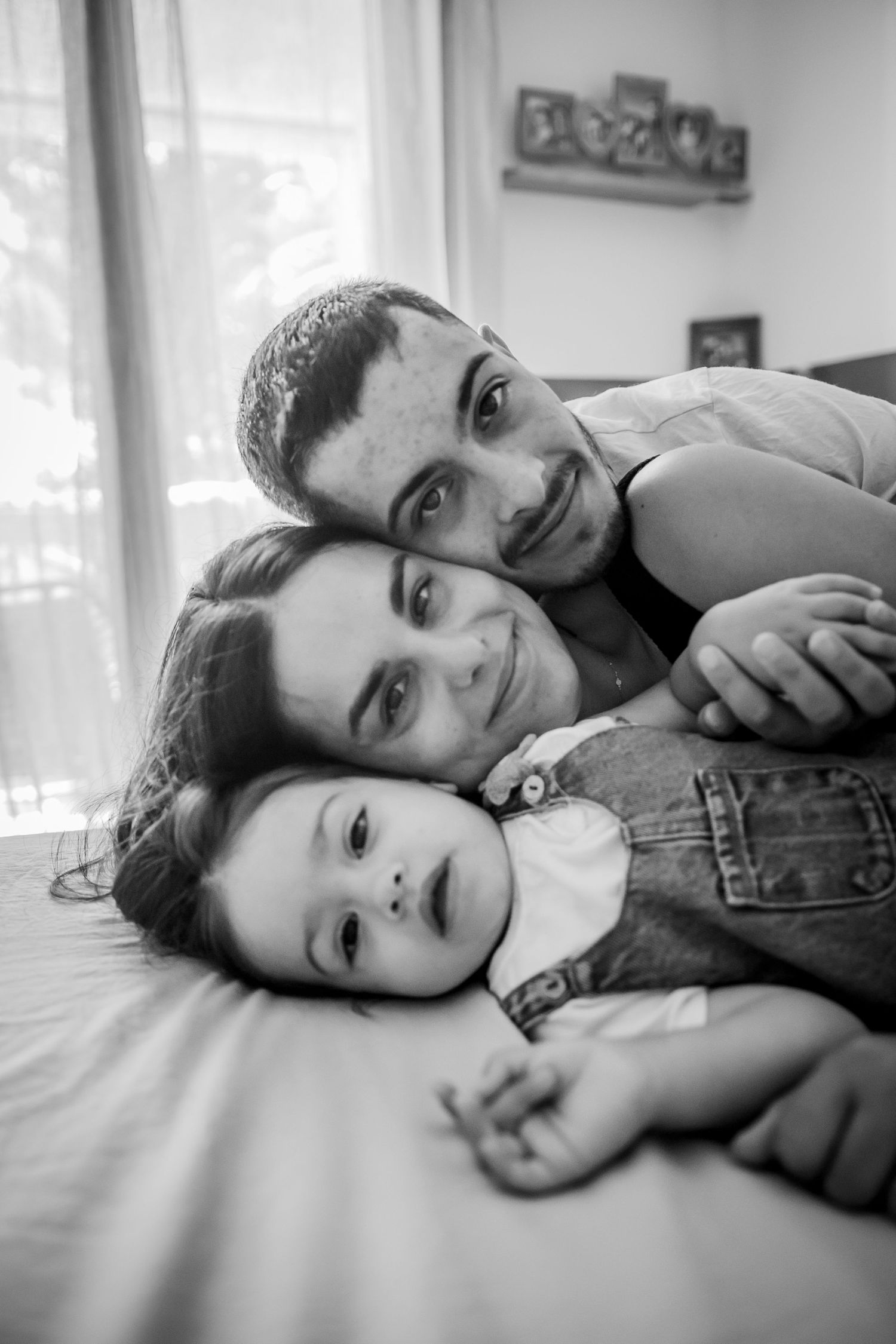 Intimate black and white portrait of couple resting together on bed.