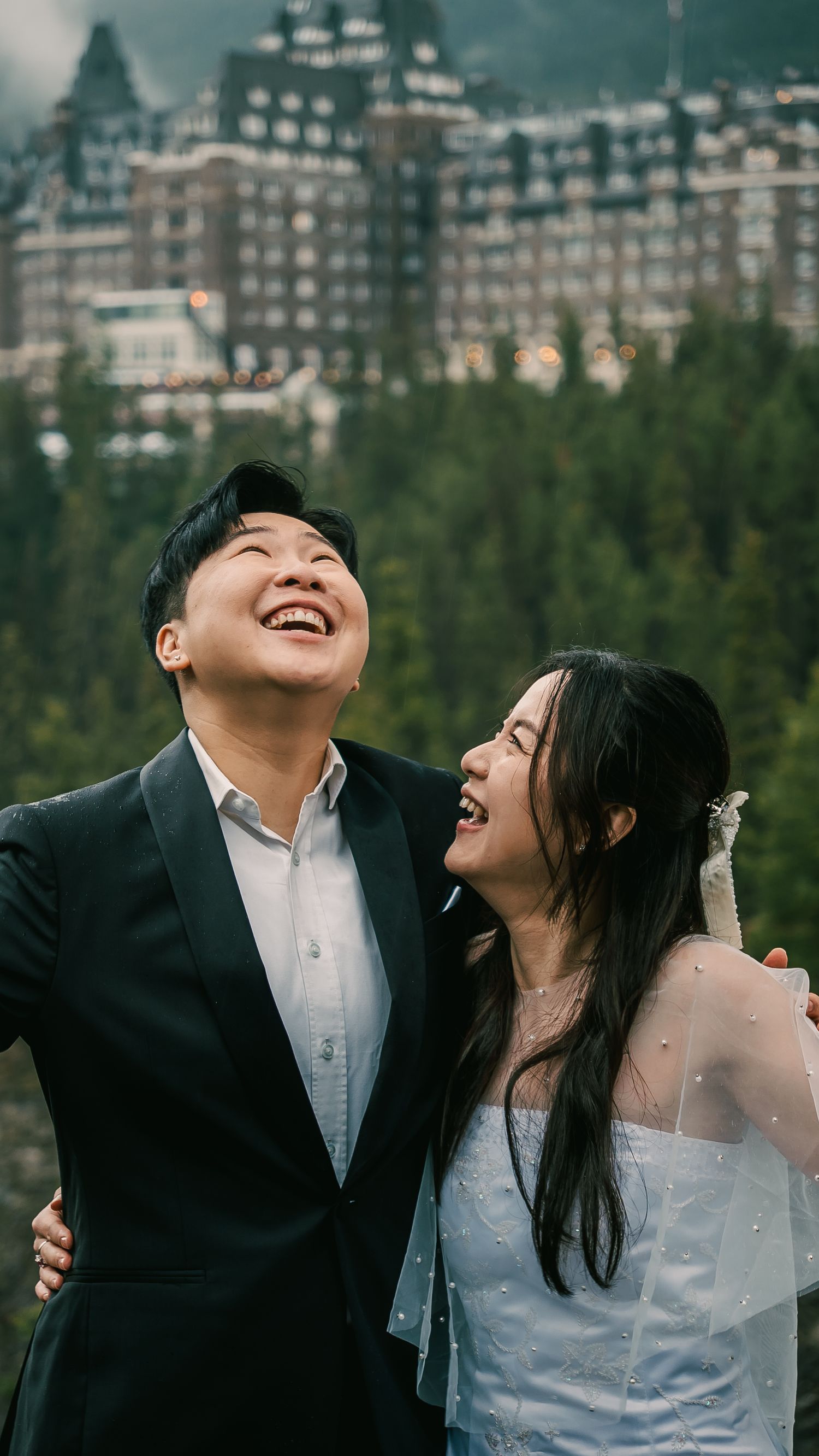 A joyful moment captured between a couple laughing together against a mountain resort backdrop.
