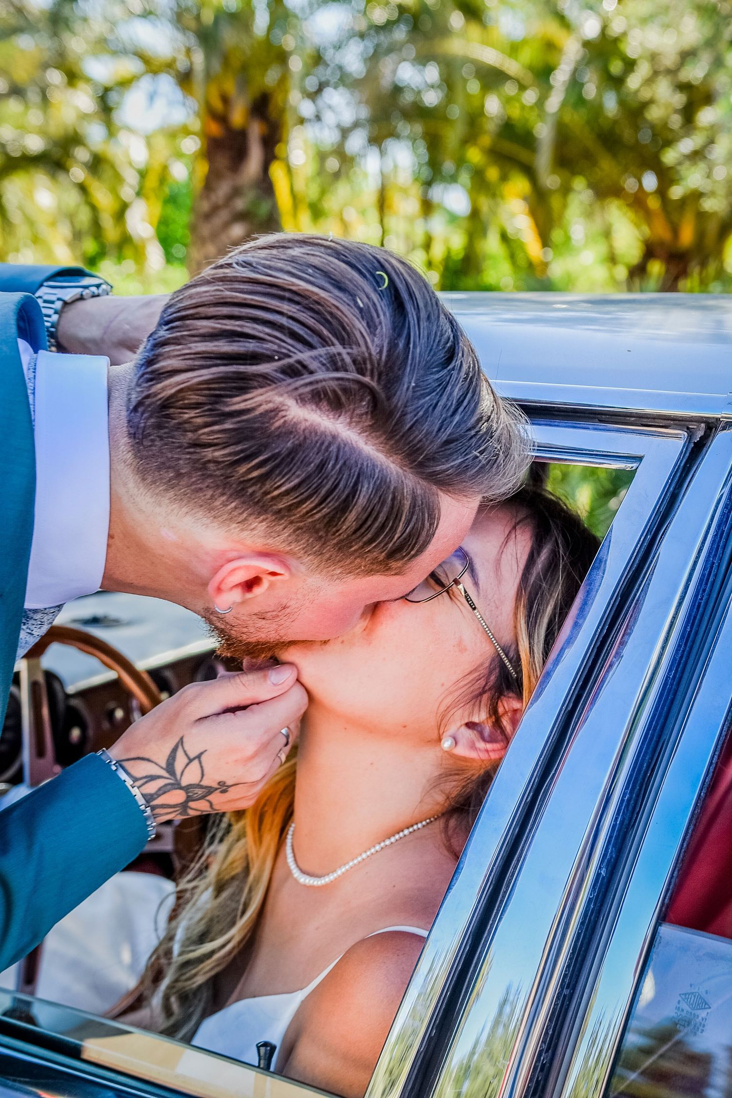 View through blue car window showing modern hairstyles and tattoo details.