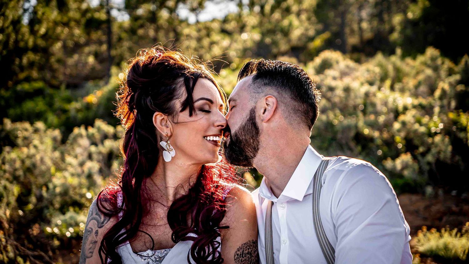 A joyful couple share a romantic moment outdoors in a garden setting on their wedding day.