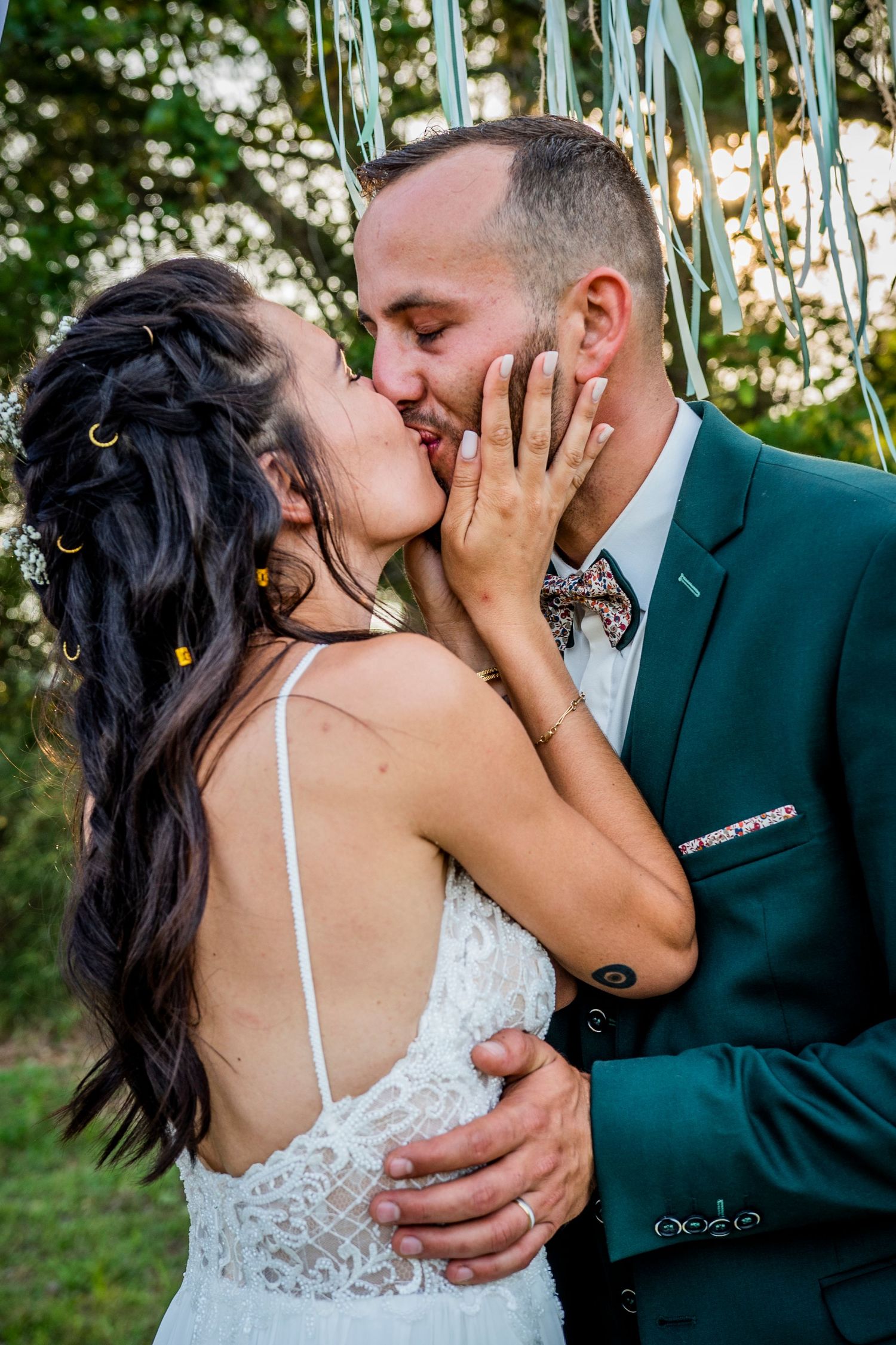 Intimate wedding moment with couple in white dress and dark suit among garden greenery.