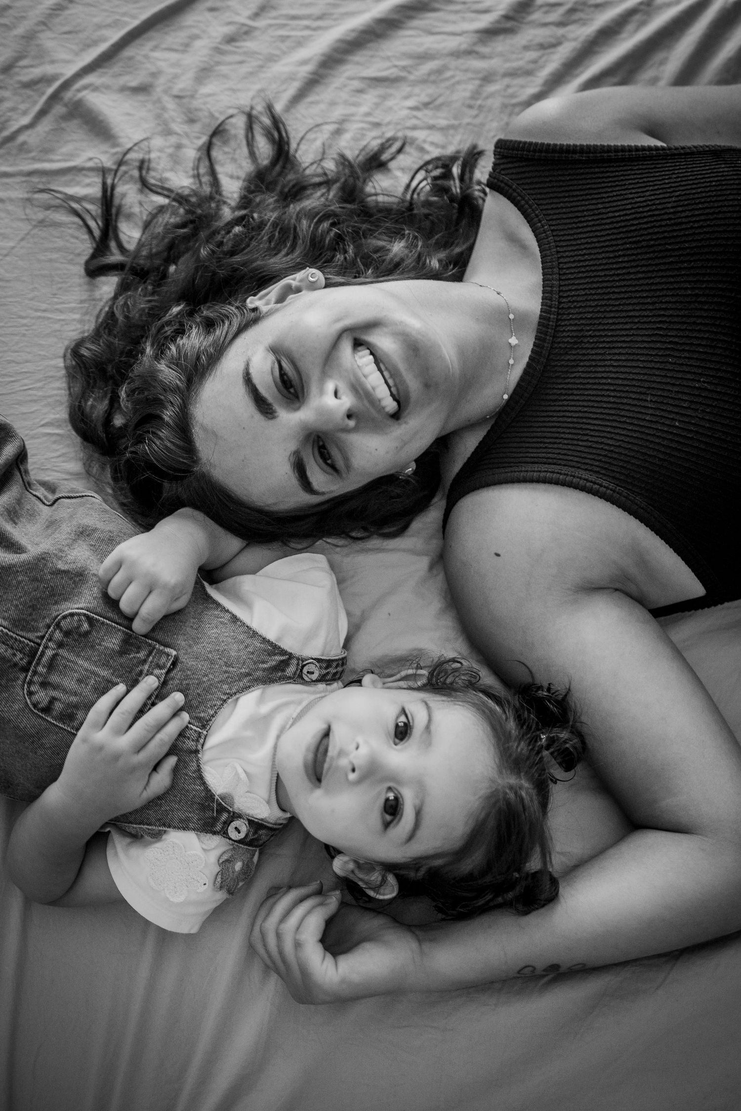 Black and white portrait of mother and child laying together with joyful expressions.