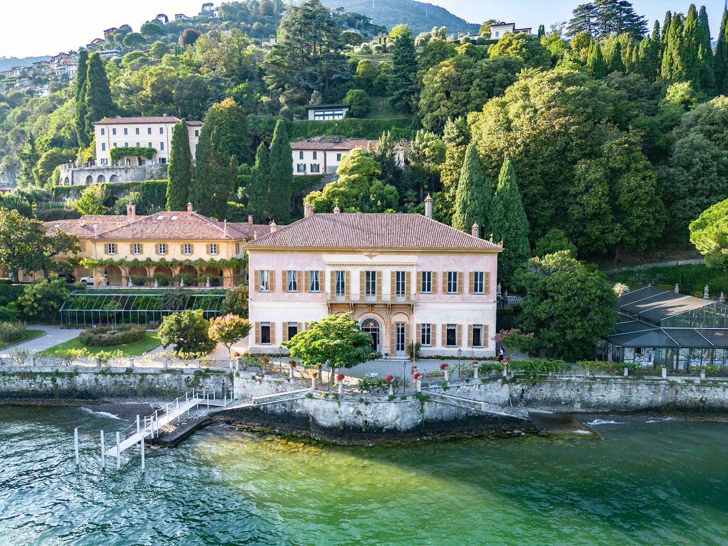 Aerial view of a stunning lakeside Italian villa with terracotta roof surrounded by lush greenery on Lake Como.