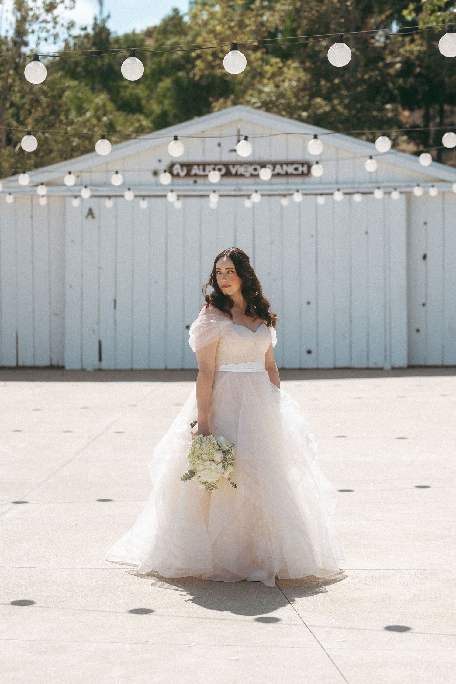 Bride in a flowing blush tulle ball gown holding a white bouquet at Aliso Viejo Ranch wedding venue.