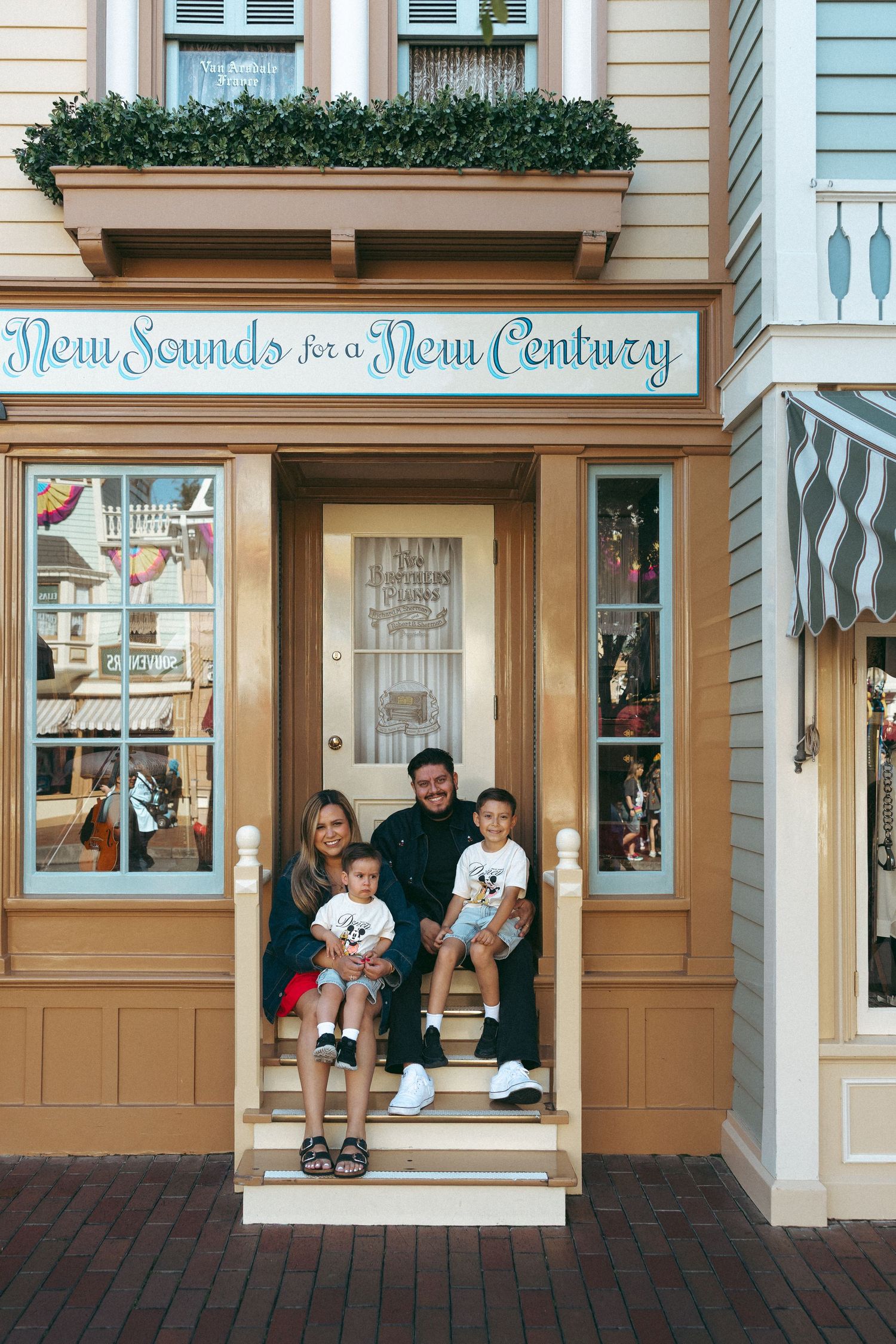 Family of four posing on steps of New Sounds for a New Century building at Disneyland park.
