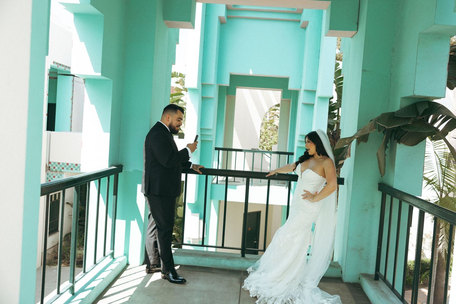 Bride in white gown and groom in black tuxedo share a first look moment on a turquoise balcony. Beverly Hill City Hall elopement.