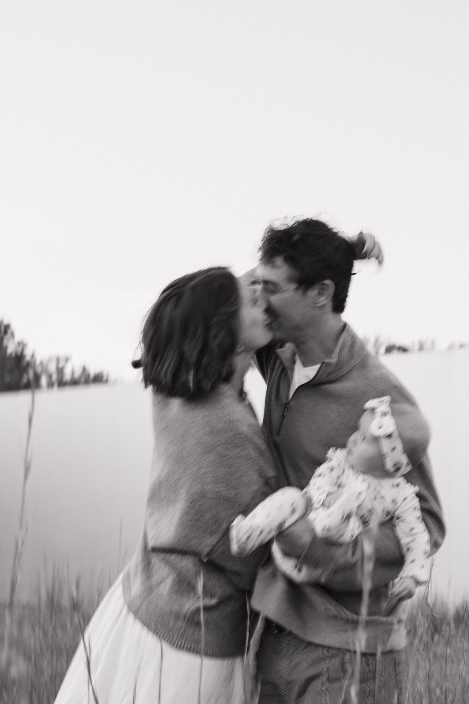 Black and white photos show a romantic couple embracing in a field with tall grass.