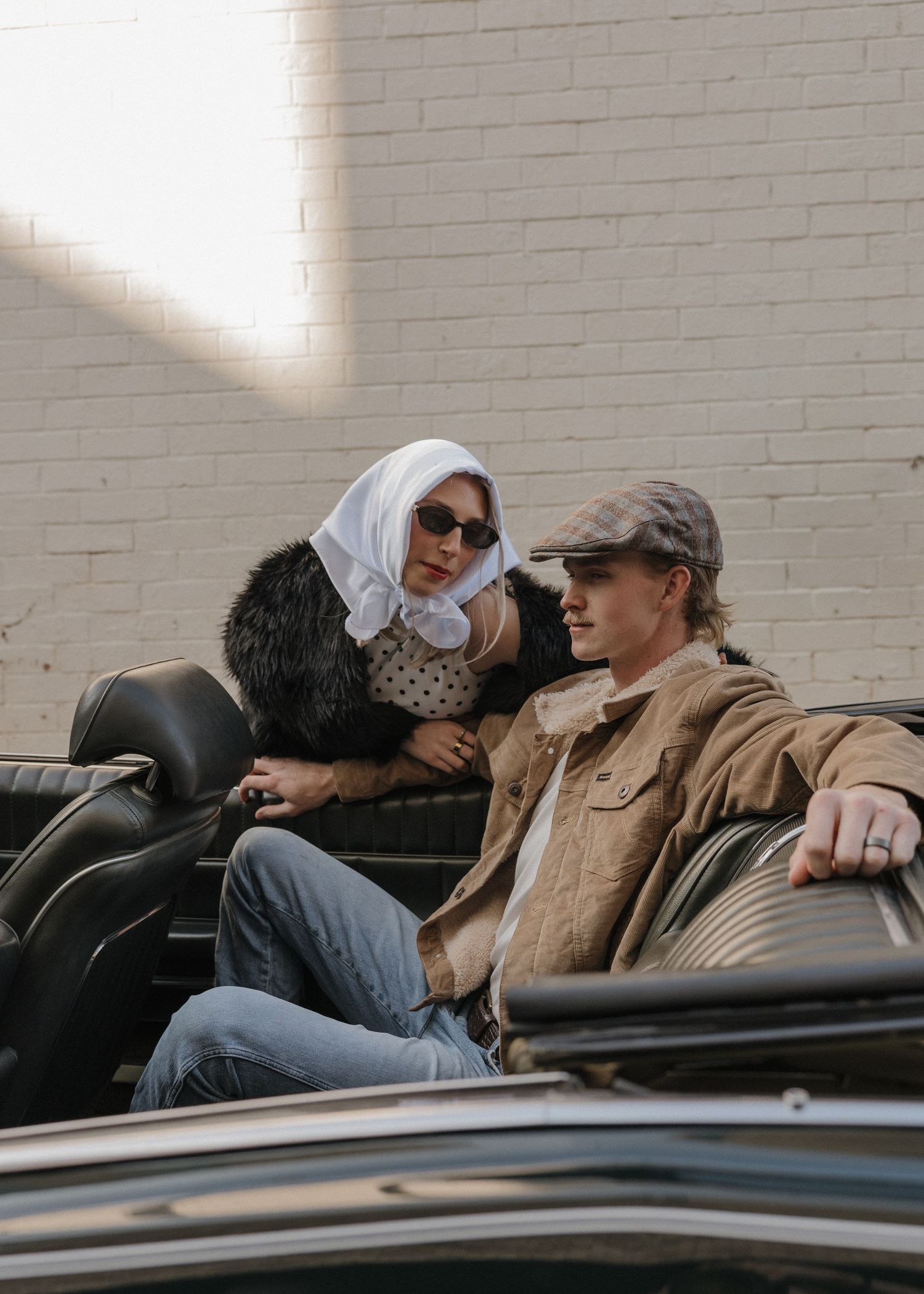 Two people relax and recline in a black leather car seat.
