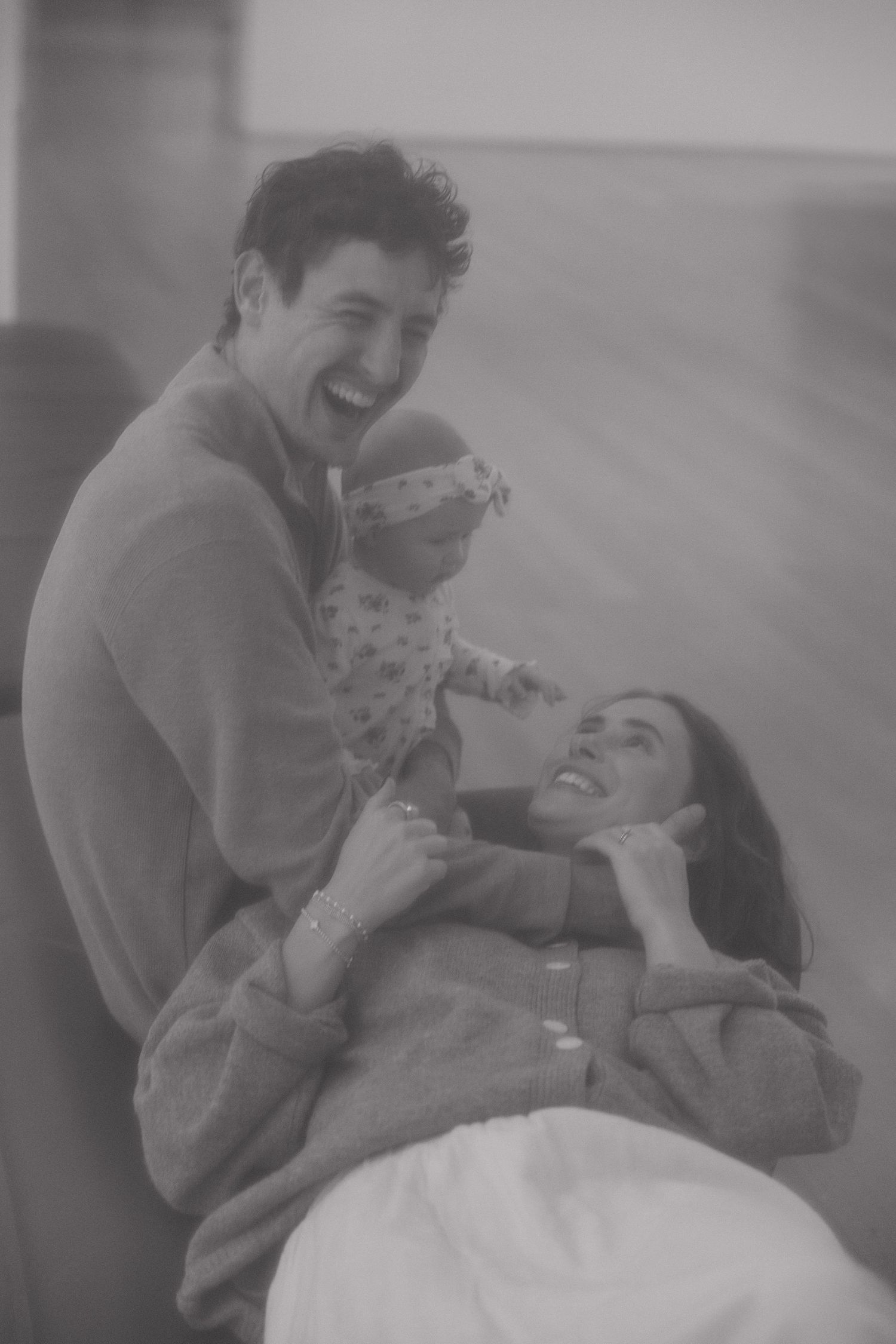 A vintage black and white photograph shows a joyful candid moment between a couple laughing together.